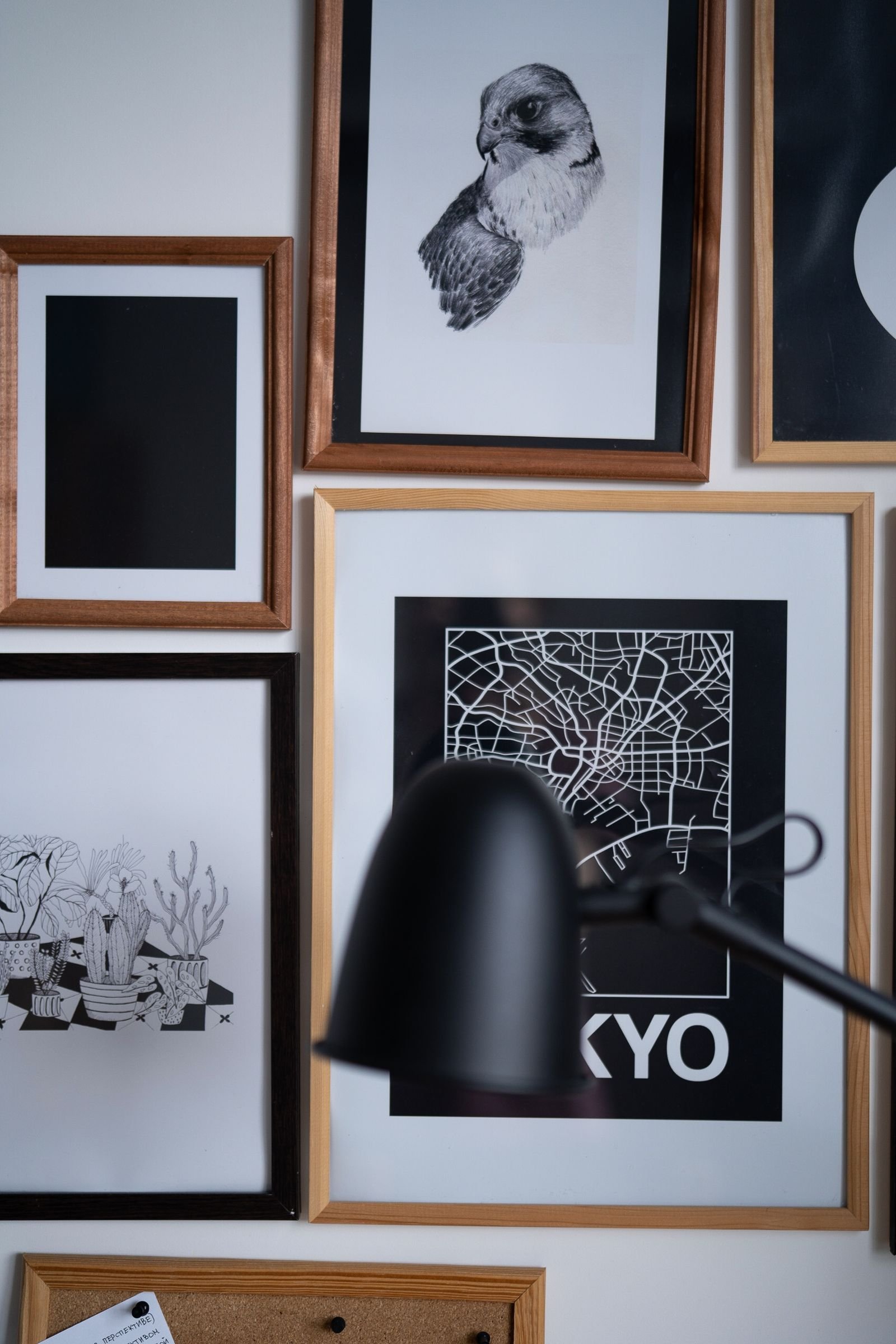 Framed prints on a wall beside a desk lamp.