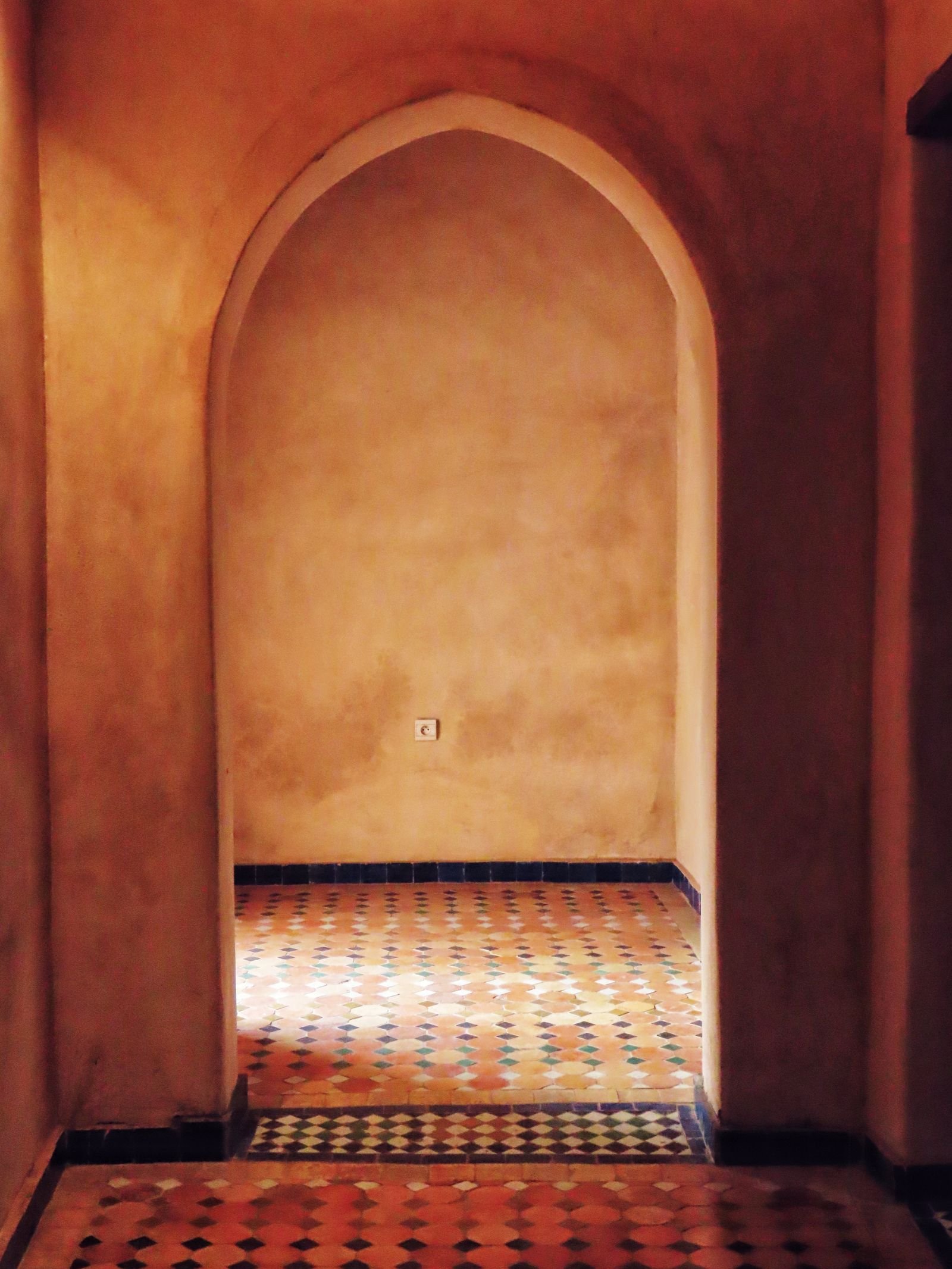 Warm arched passage in a house with a patterned tile floor.