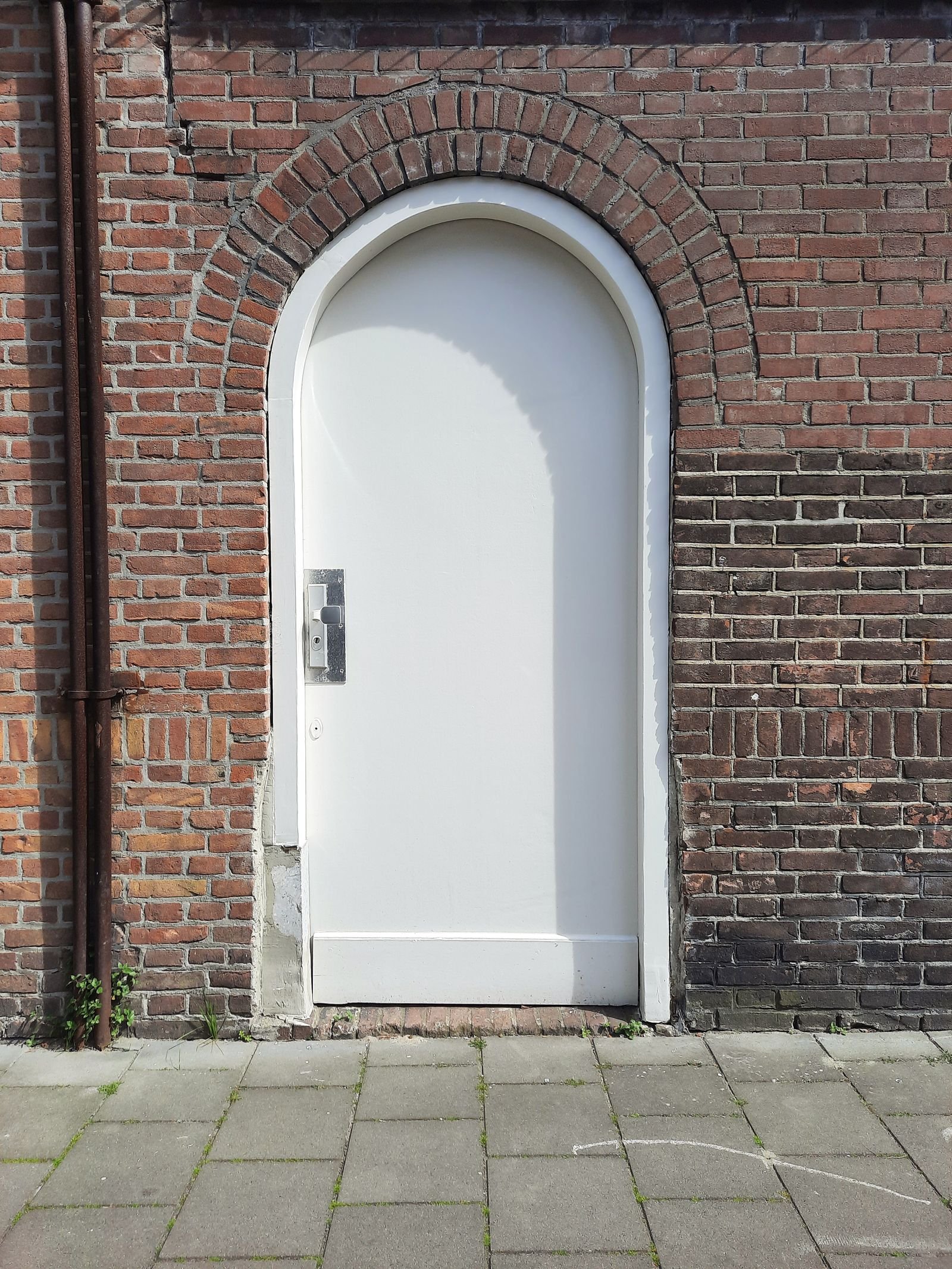 White arched door set in a red brick wall.