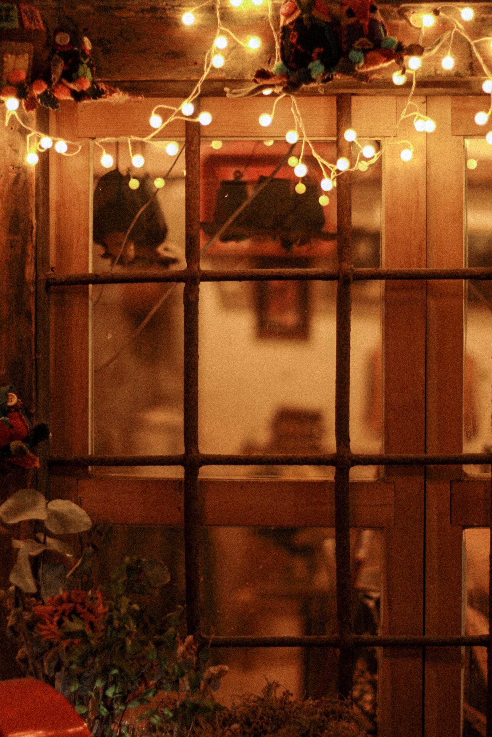 House window decorated with glowing fairy lights on an evening.