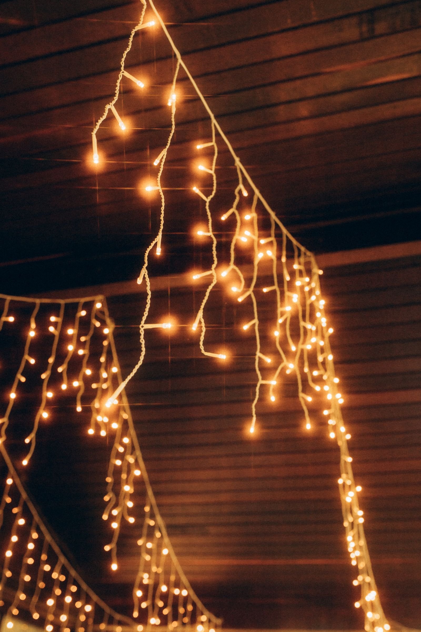Golden fairy lights hanging against a wooden ceiling in a cozy room.
