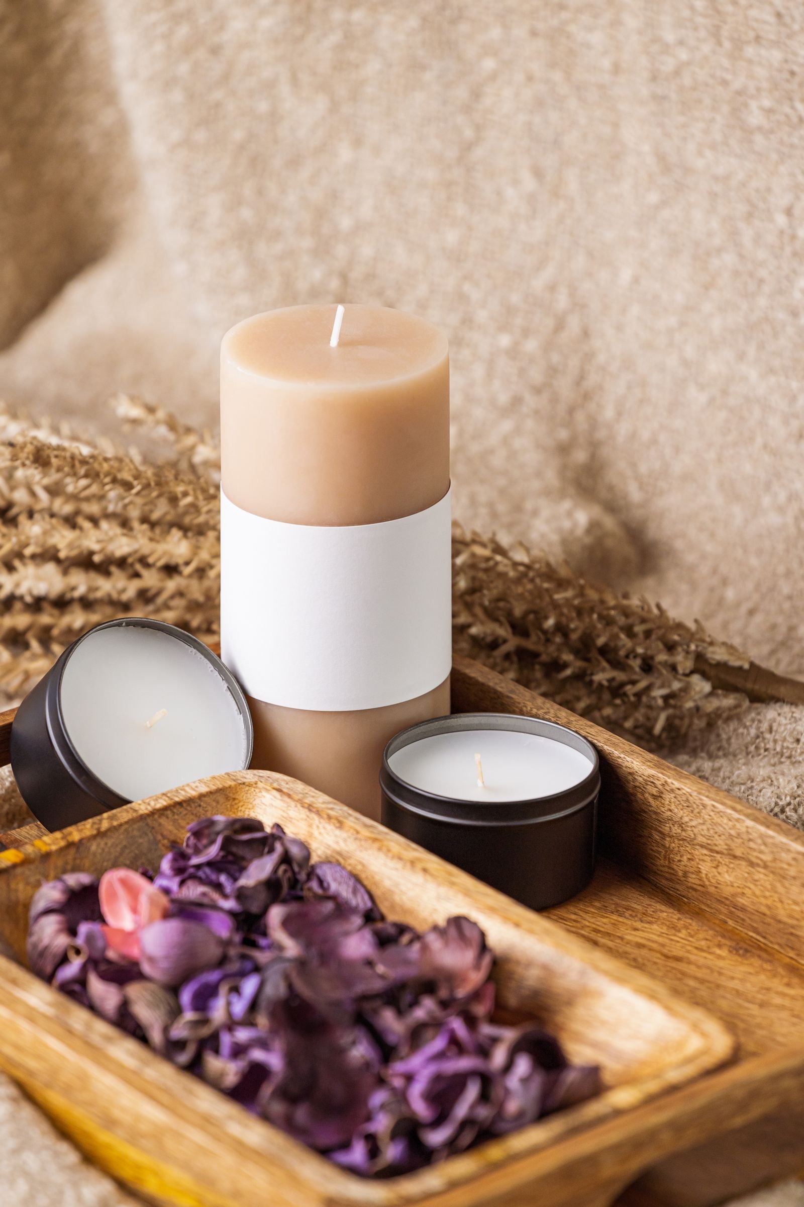 Candles and potpourri arranged on a brown wooden tray.