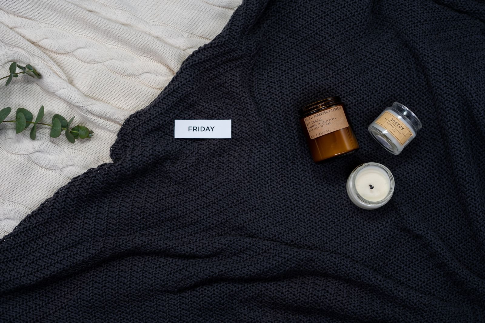 Knitted blanket with candles and eucalyptus for a cozy mood.