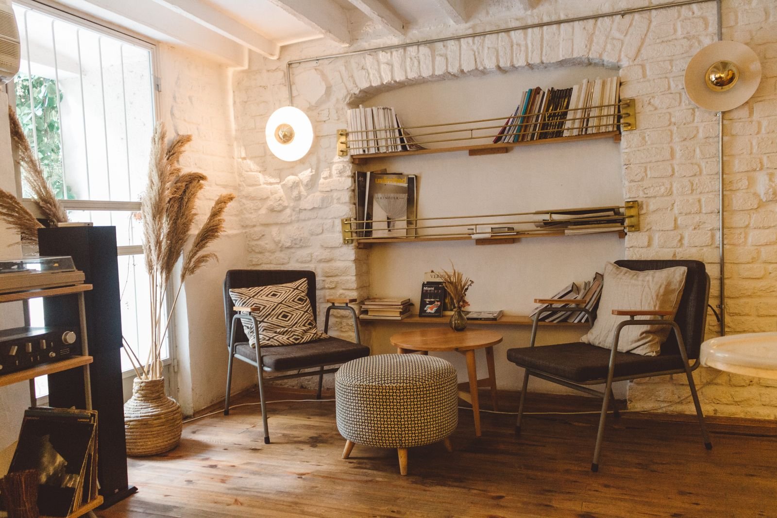 Modern rustic living room with armchairs, an ottoman and a bookshelf.