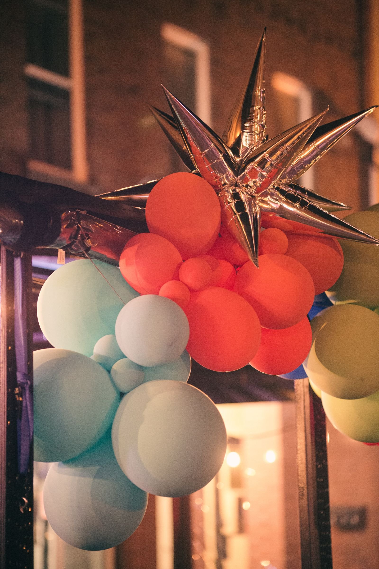 Colorful balloons and a metallic star hanging together as a festive decoration.