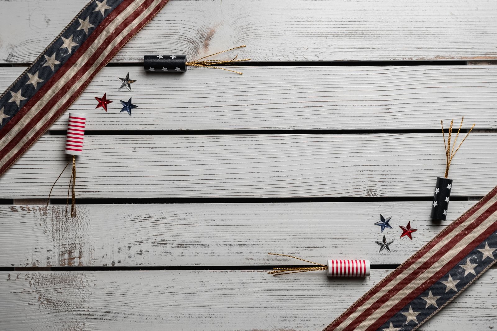 Small U.S. flags, stars and fireworks laid out on a wooden table.