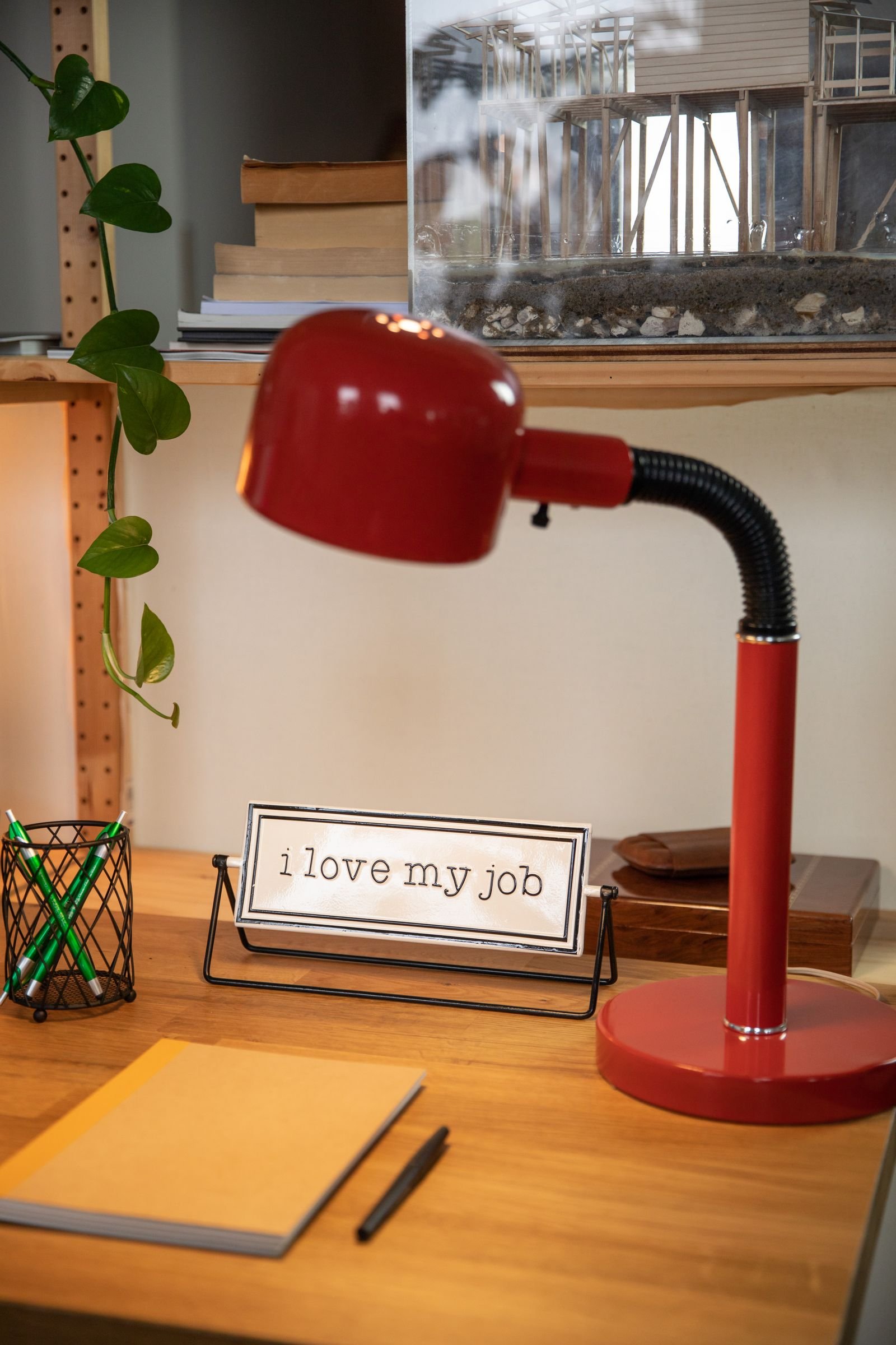 Tidy wooden desk with a red lamp, books and small decorations.