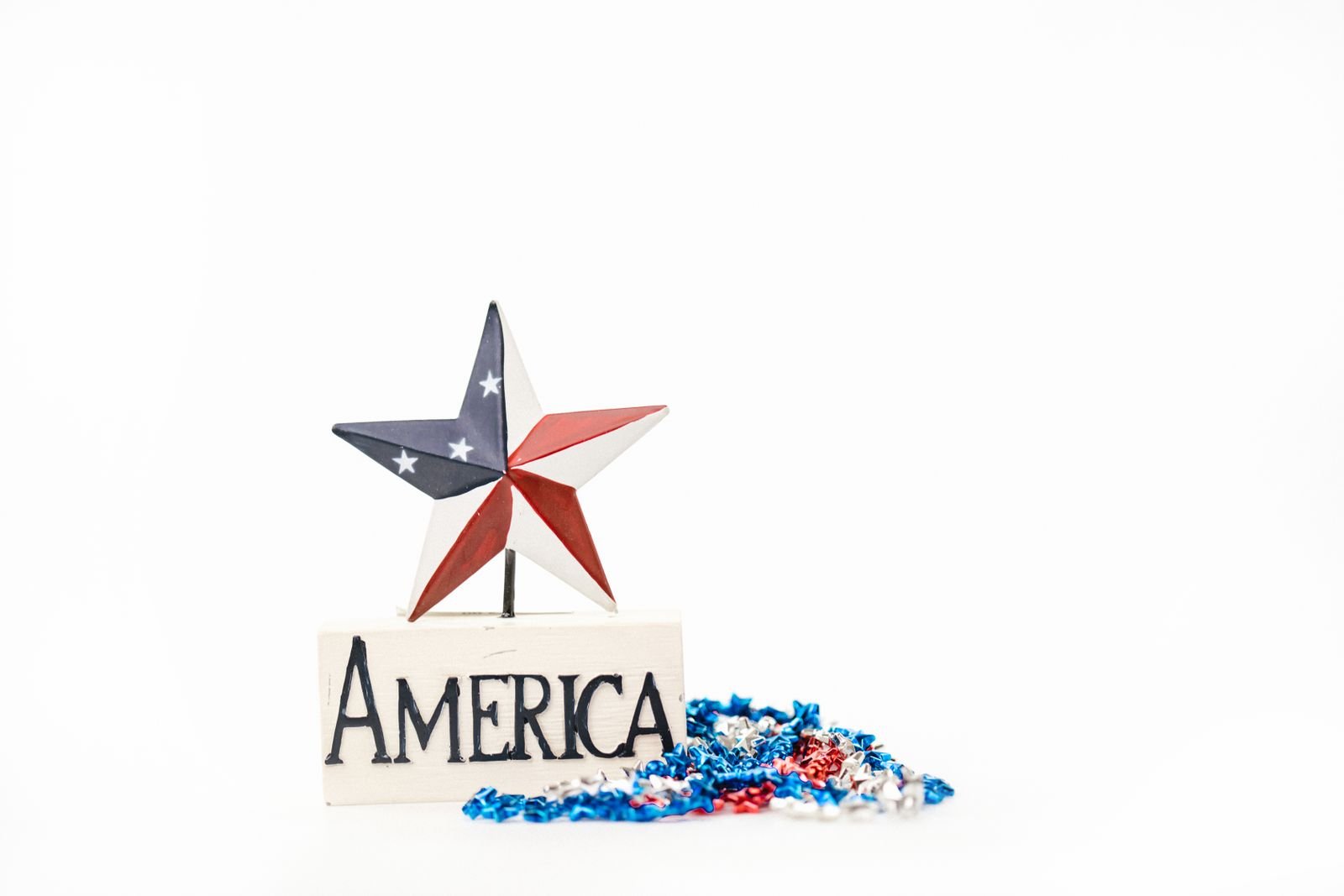 Small red, white and blue star decoration with tinsel on a pedestal.