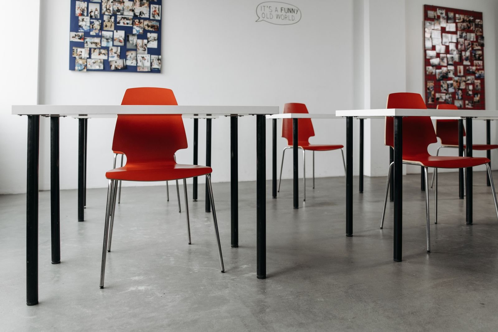 Classroom with red chairs, white tables and photo collages on the walls.