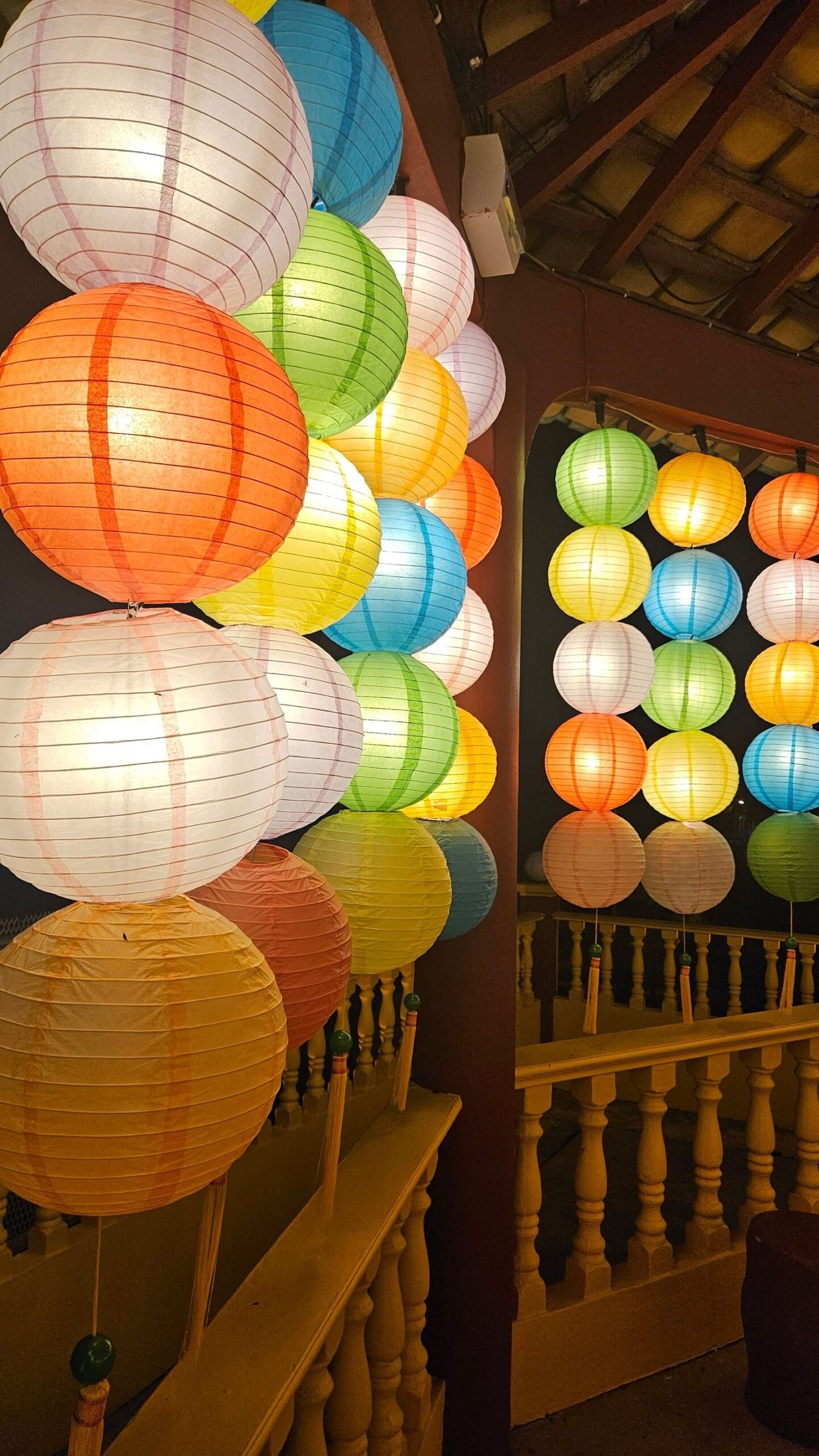 Colorful paper lanterns glowing in an indoor space.