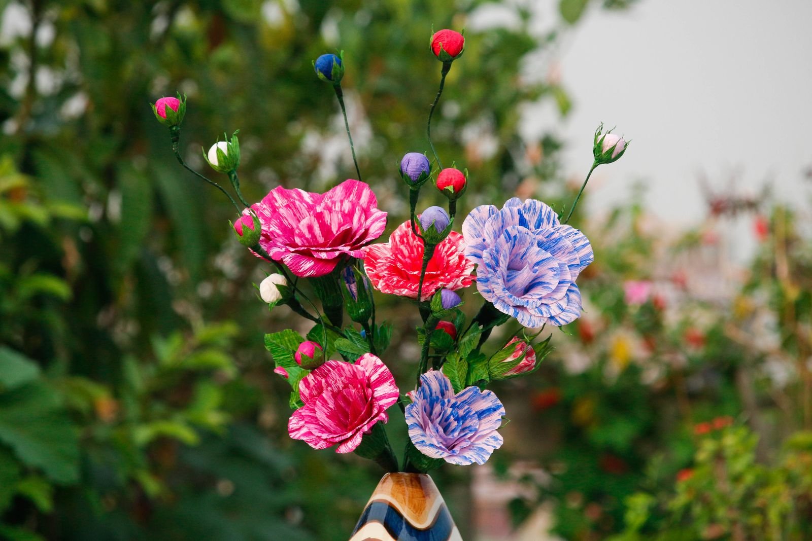 Red and blue handmade paper flowers with green leaves.