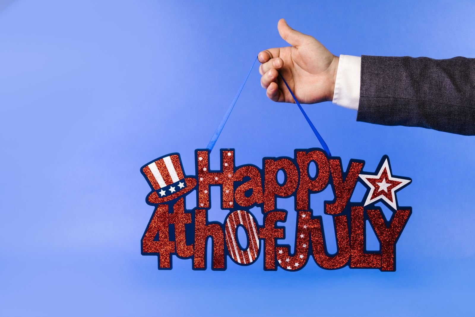 Glittery 4th of July sign with stars and stripes on a blue backdrop.