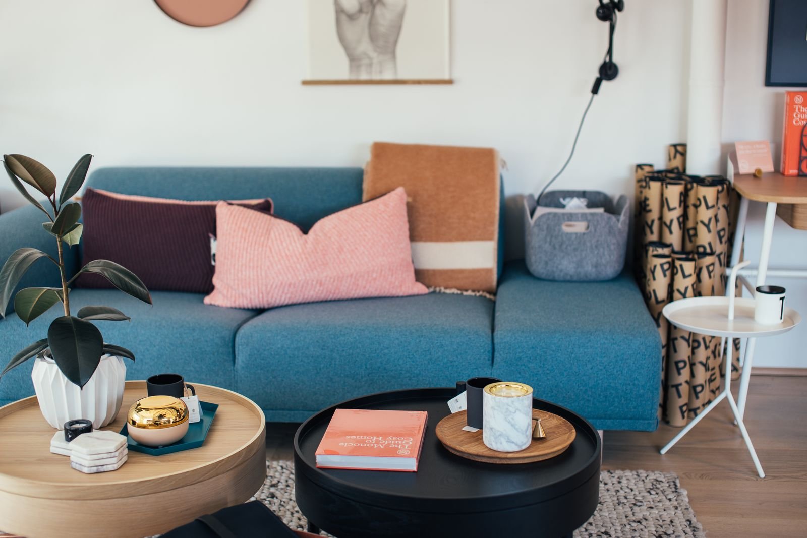 Cozy sofa with cushions beside round coffee tables with a plant and candles.
