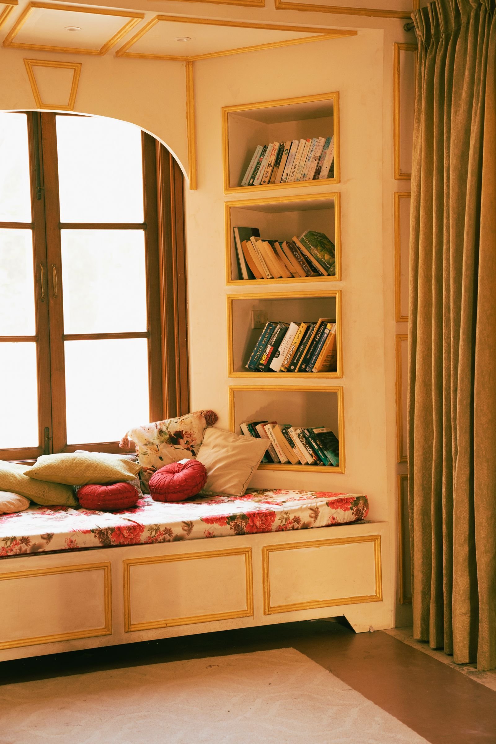 Cushioned window seat with pillows and built-in bookshelves.