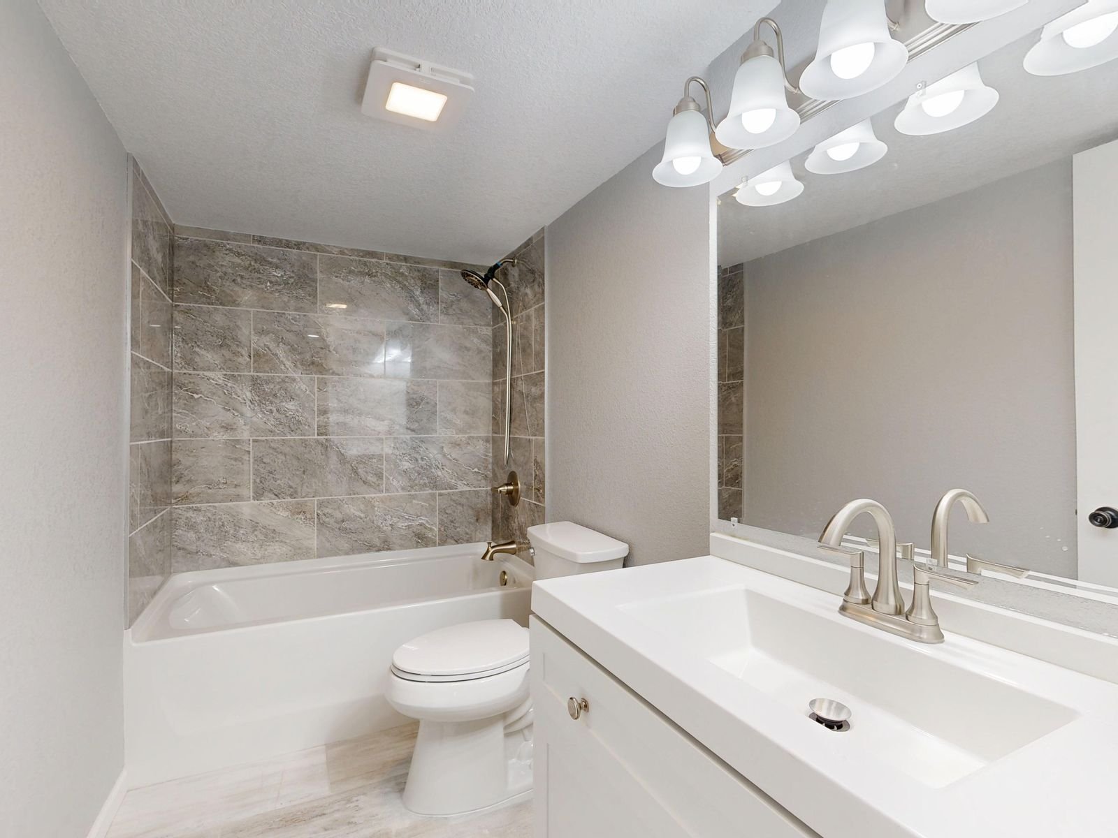 Modern bathroom with marble tiles and a sleek white vanity.