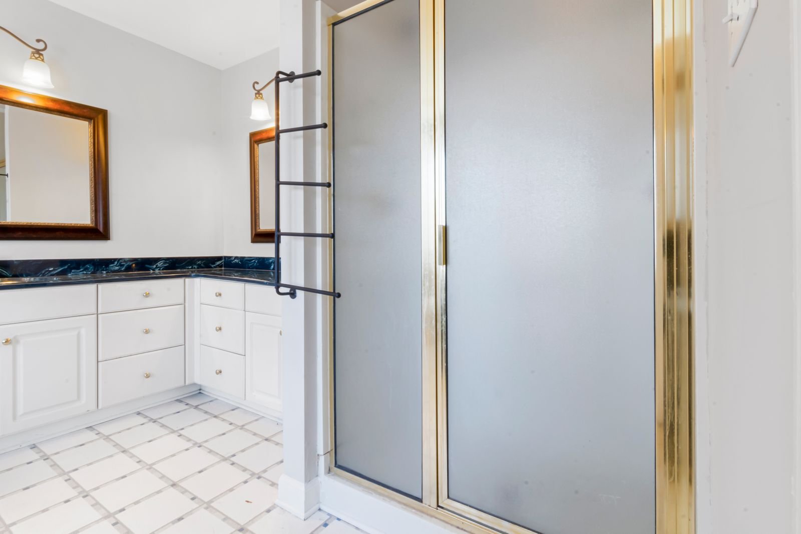 Bathroom with a gold-trimmed shower and marble countertops.