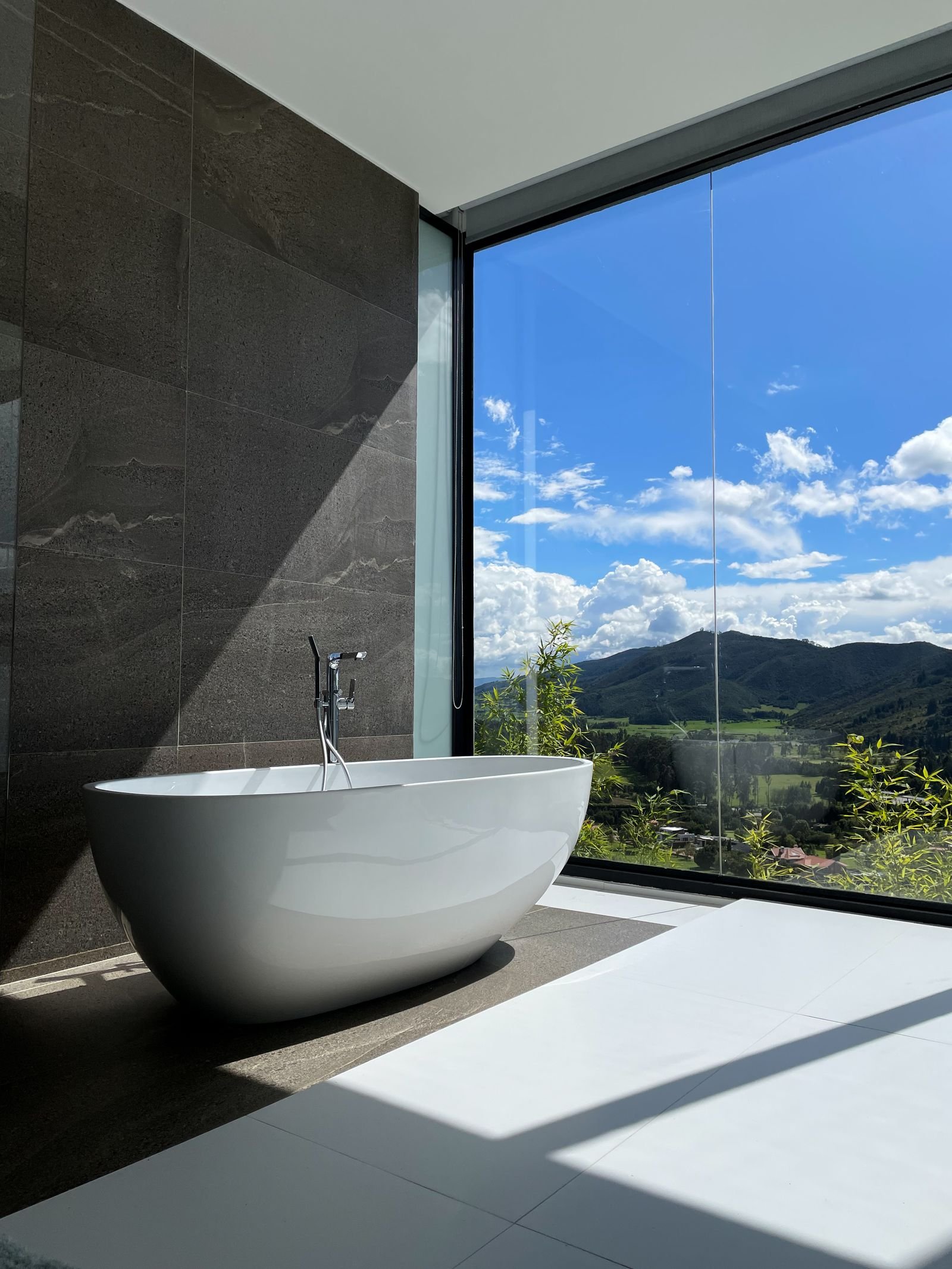 Bathtub beside a large window with a wide mountain view.