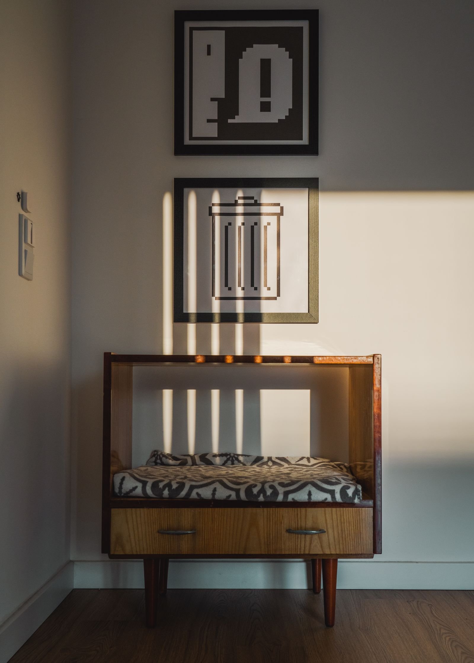 Mid-century furniture in a sunlit corner with geometric artwork.