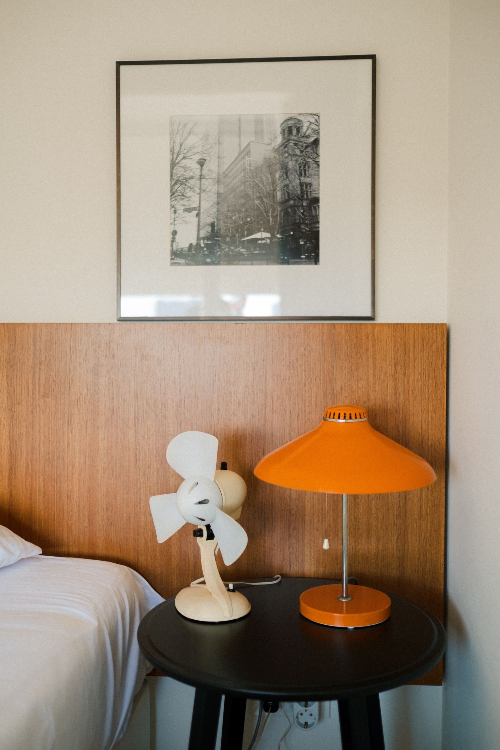 Mid-century bedroom with an orange lamp and a framed photograph.