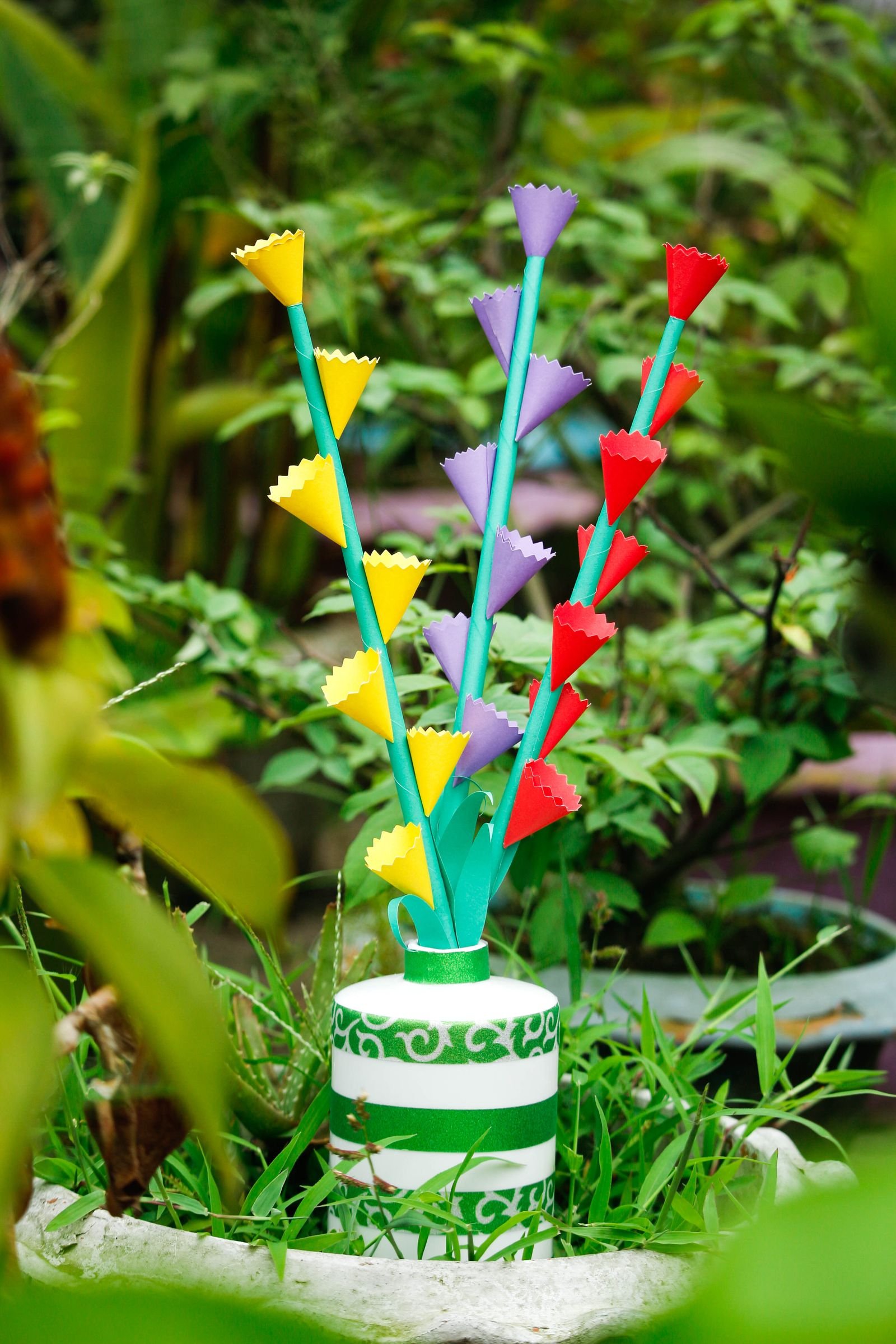 Colorful paper flowers arranged in a patterned vase.