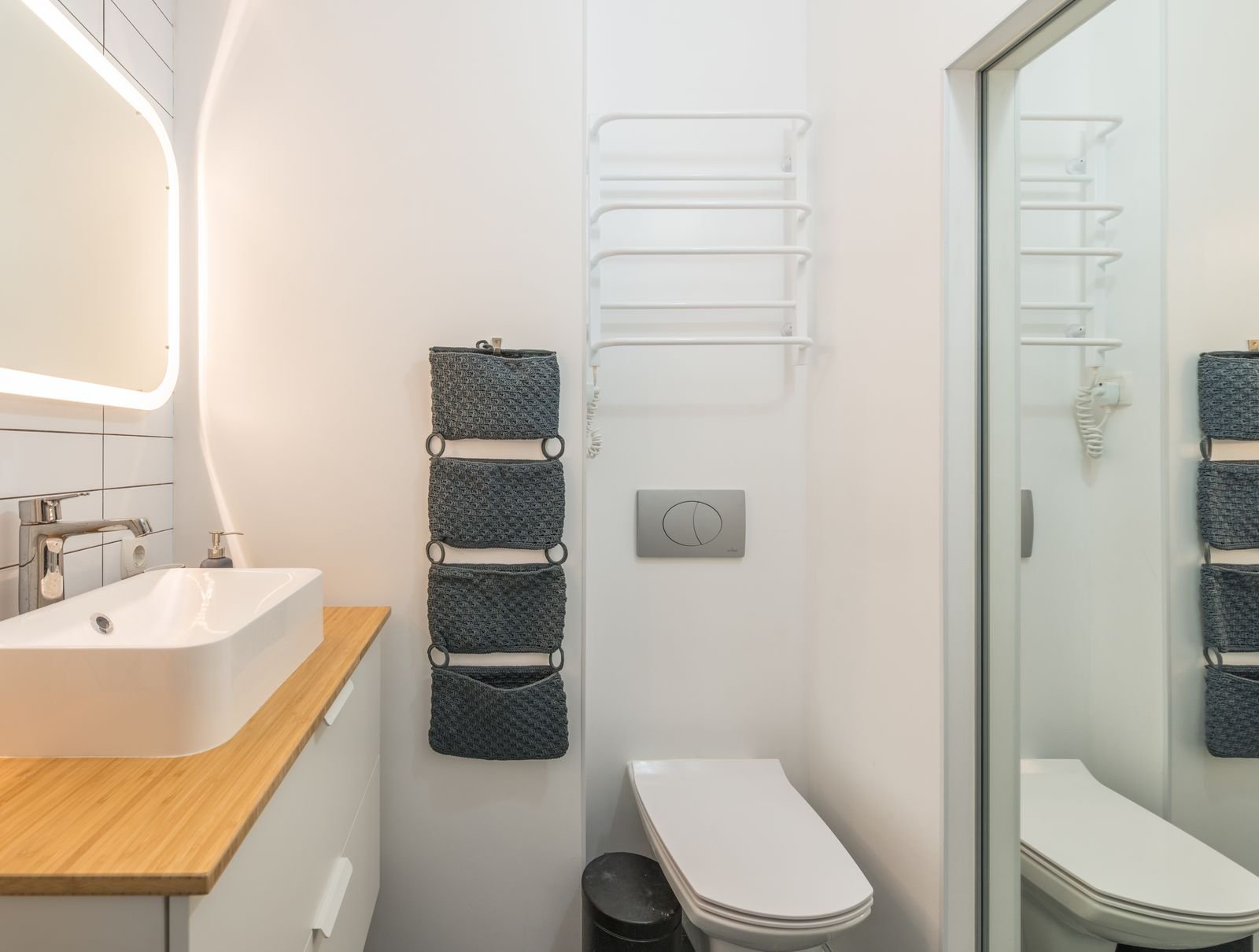 Small bathroom with a toilet and sink under a softly lit mirror.