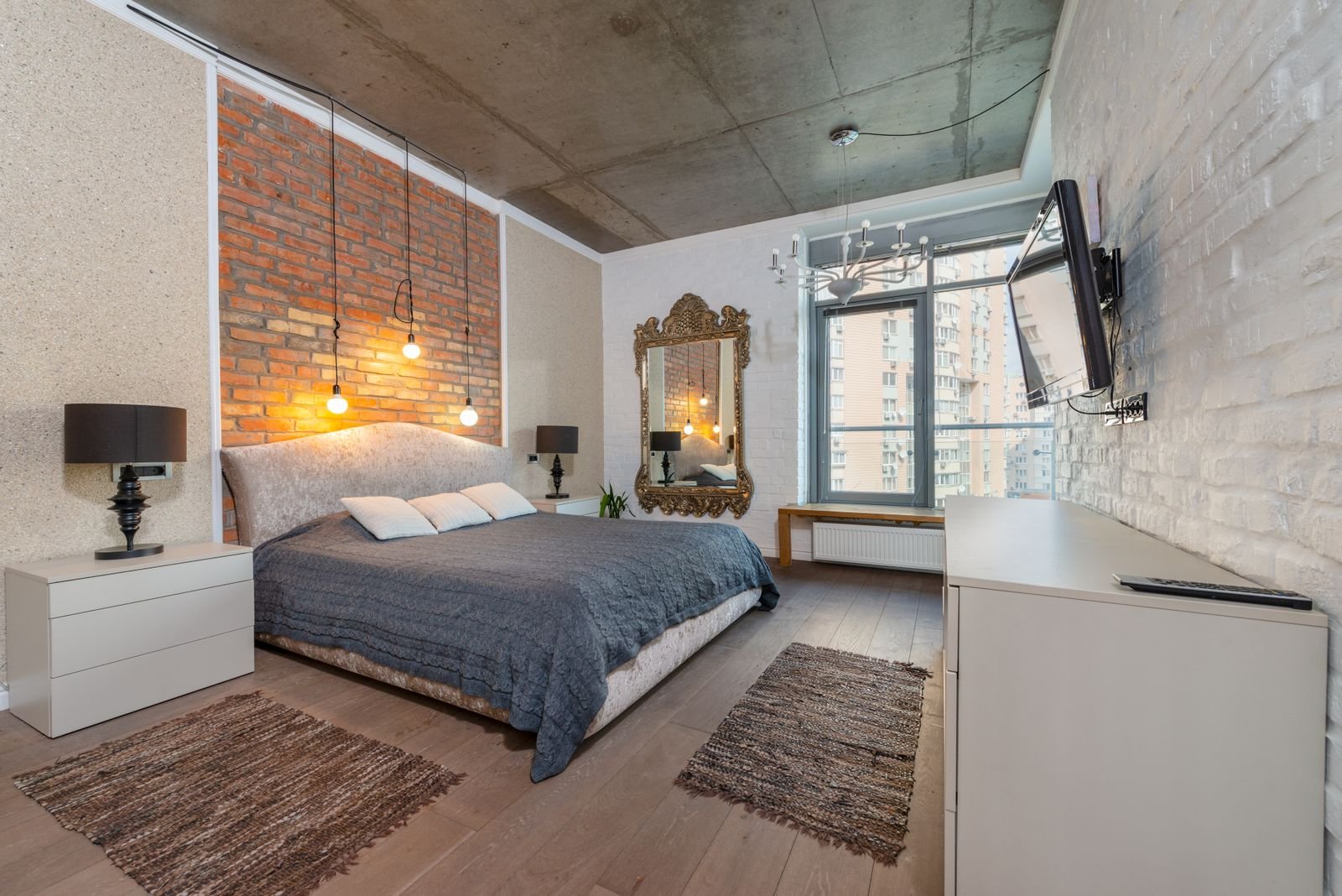 Spacious industrial-style bedroom with an exposed brick wall.