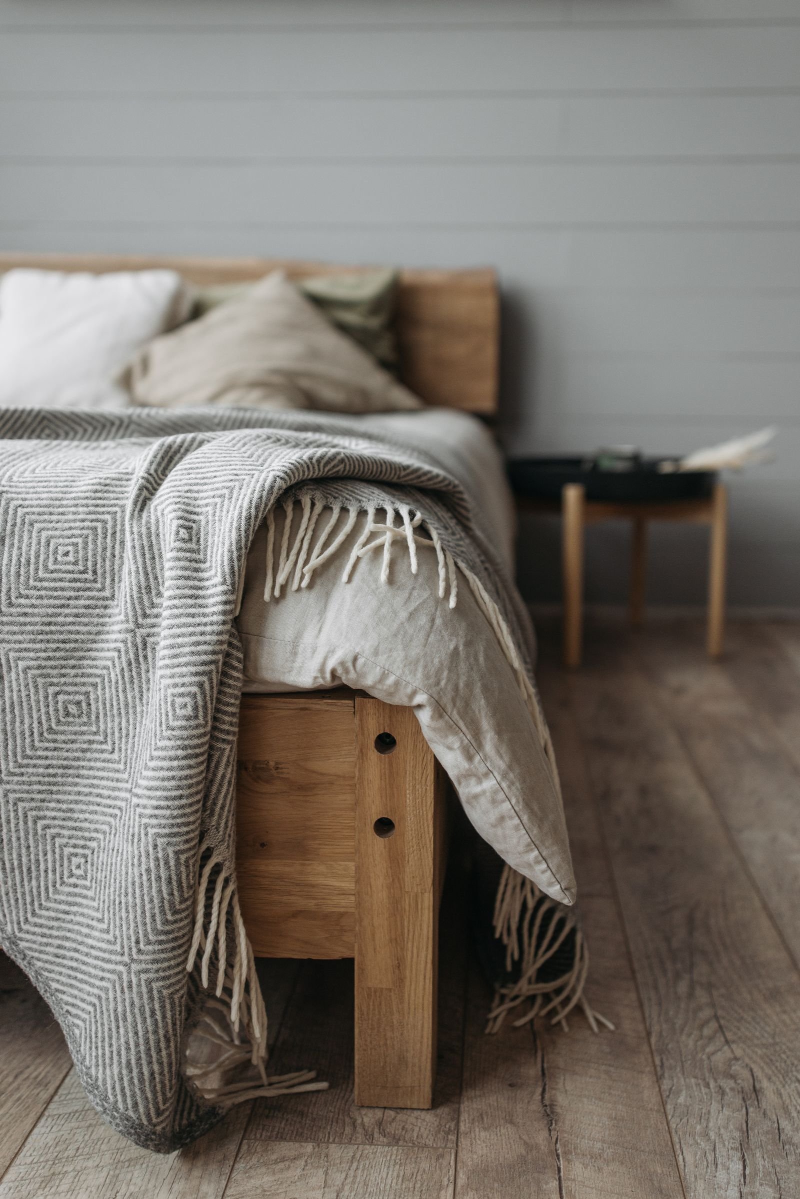 Cozy bedroom with a wooden bed, pillows and a patterned blanket.