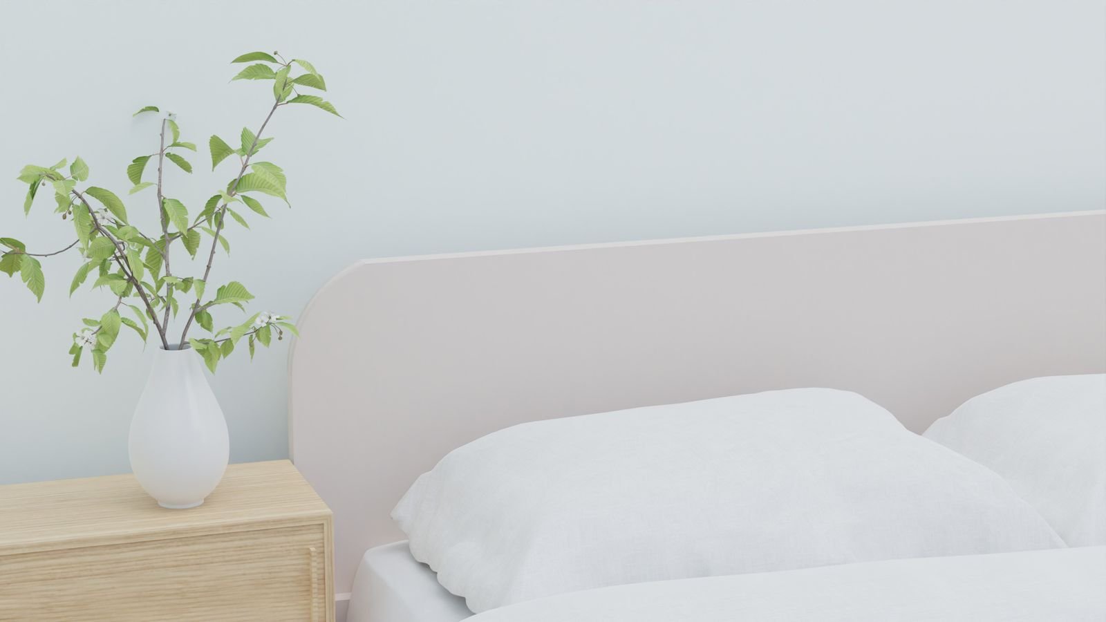 Bed with white bedding beside a wooden nightstand holding a vase of greenery.