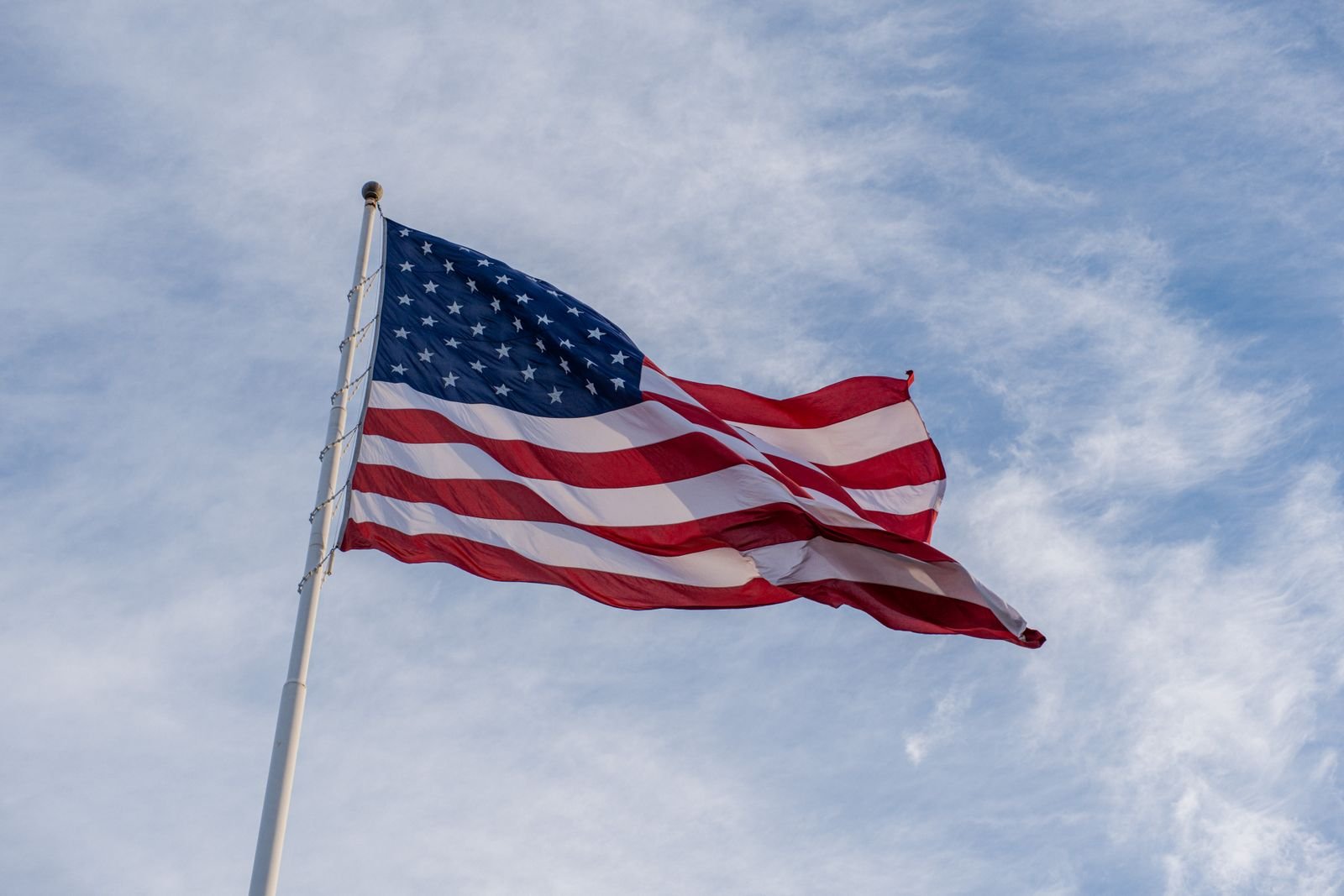 American flag waving on a pole against a blue sky.