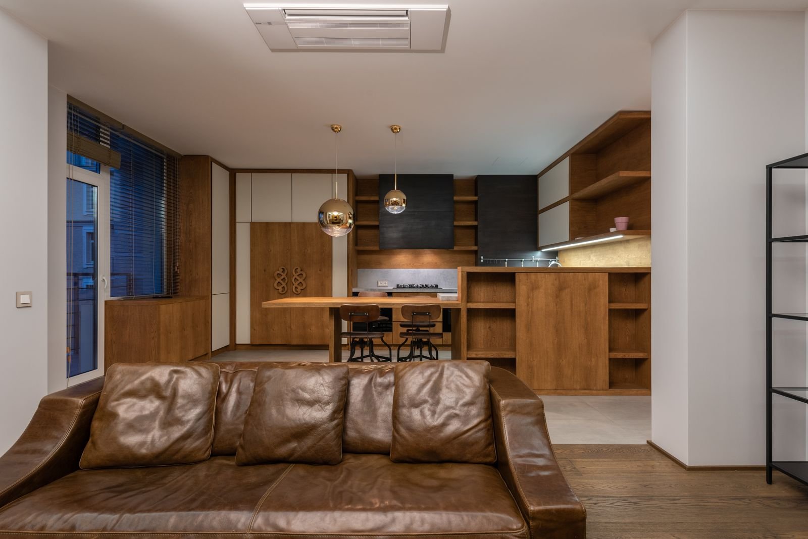 Brown leather sofa with pillows in a modern apartment with shelves.
