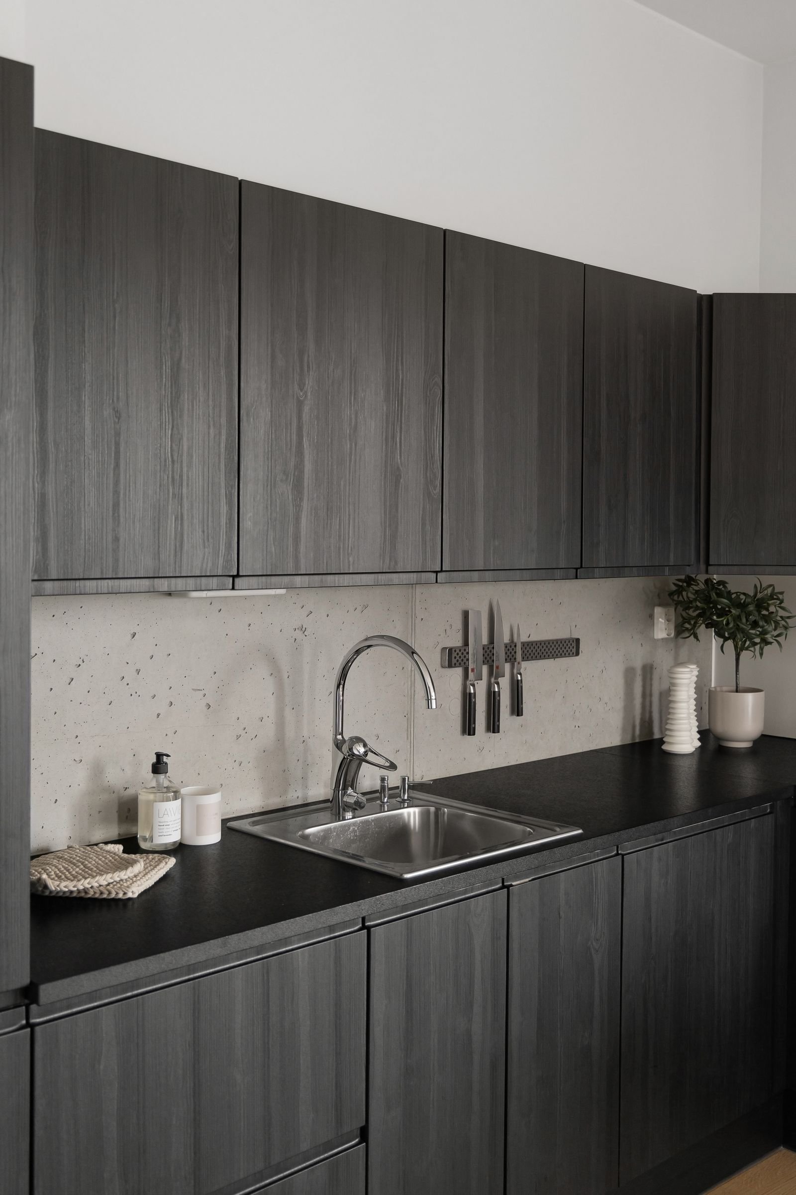 Kitchen with dark wooden cabinets and a stainless steel sink.