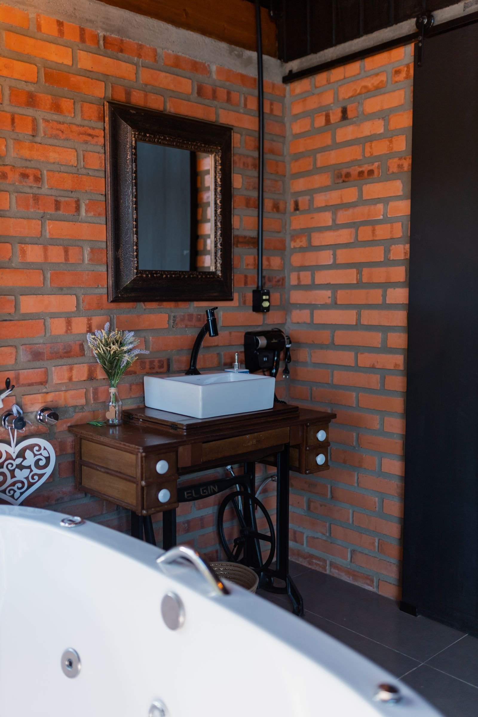 Rustic bathroom with a vintage vanity against an exposed brick wall.