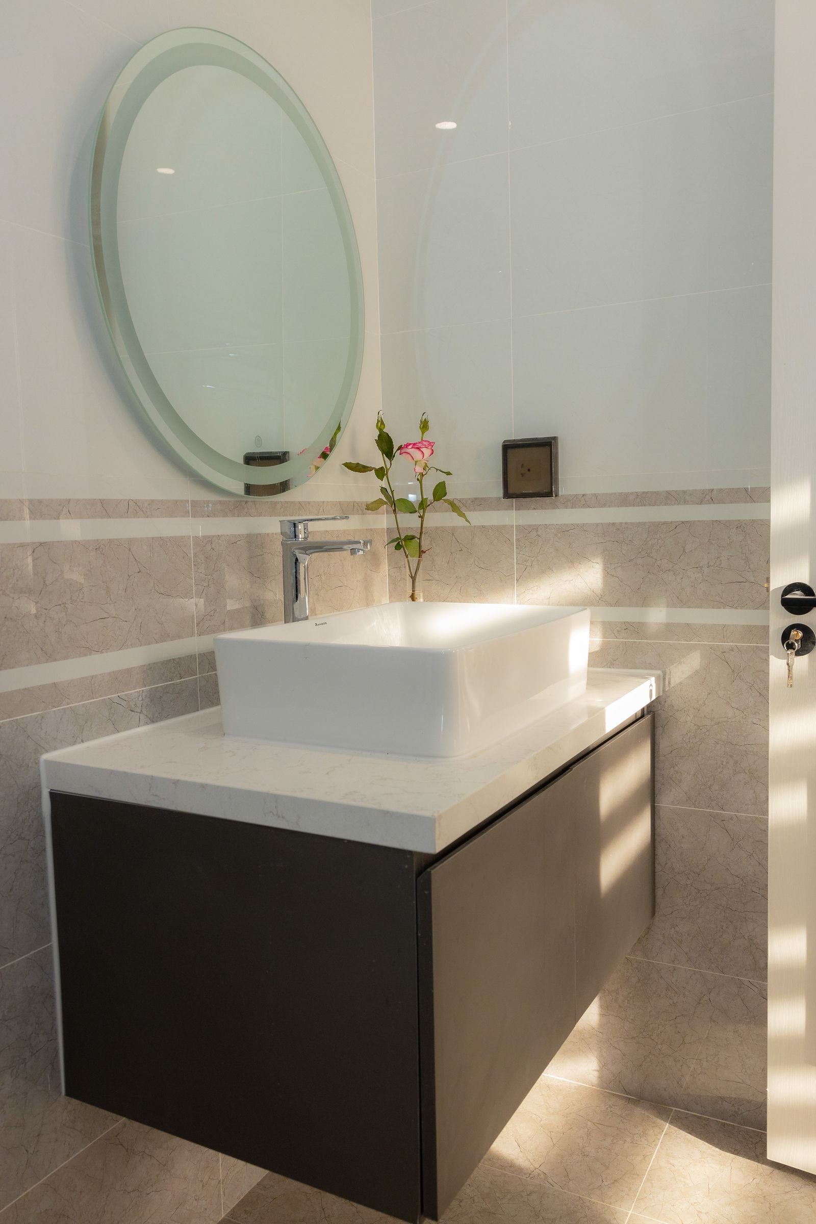 Sunlit minimalist bathroom vanity with a round mirror.