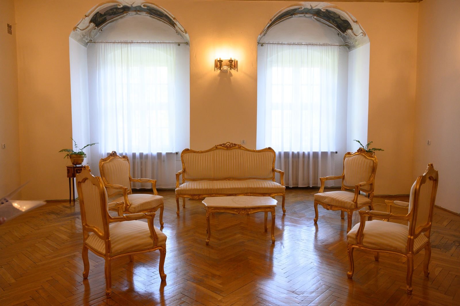 Living room with classic furniture, gold accents and parquet flooring.