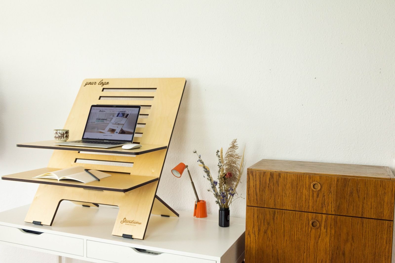 Minimalist standing desk in a home office with a laptop, a book and decor.