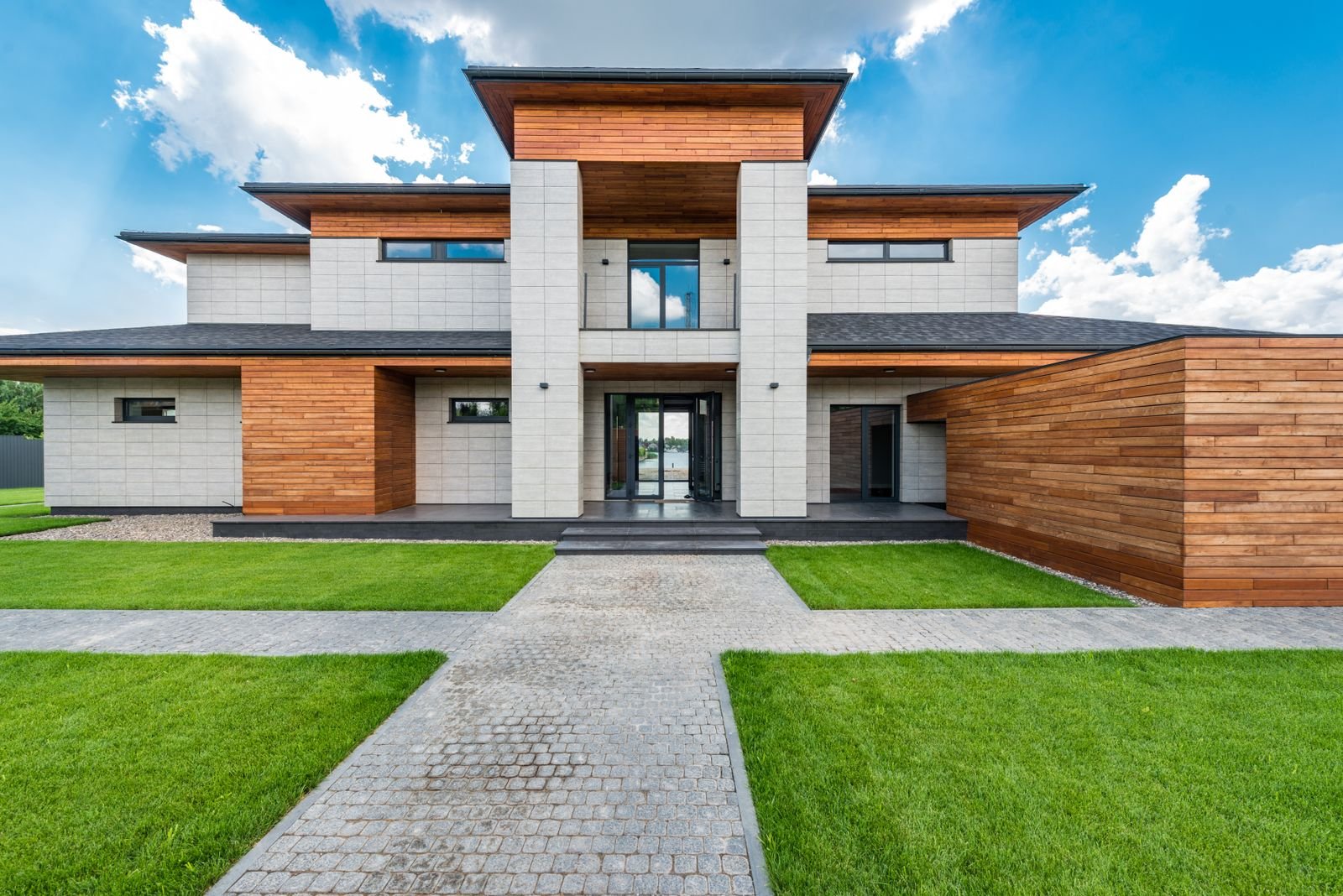 Contemporary house with a lawn and cobblestone paths in the yard.