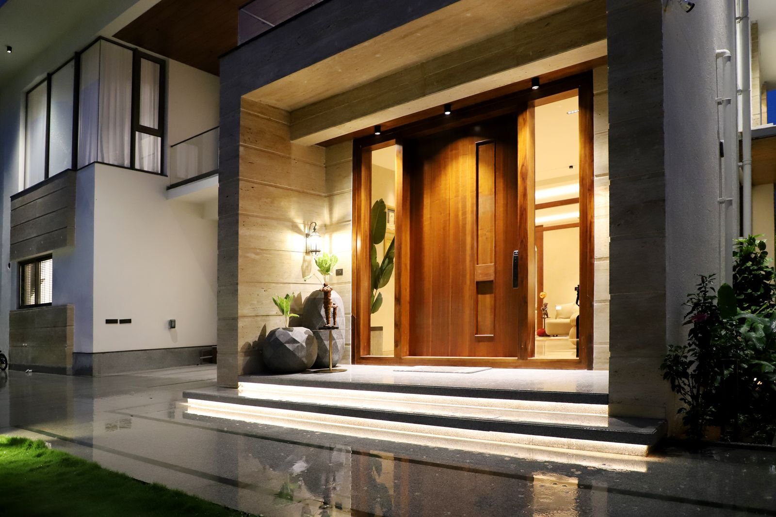 Modern house entrance lit with warm light at night.