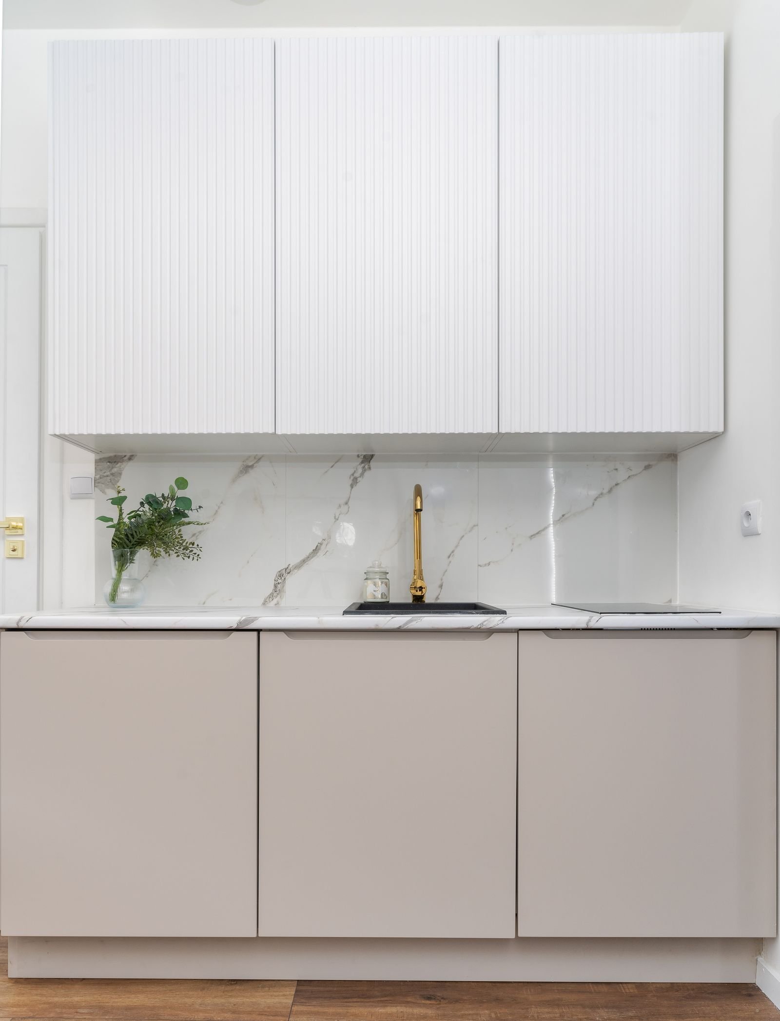 Minimalist kitchen with a marble backsplash and a gold faucet.