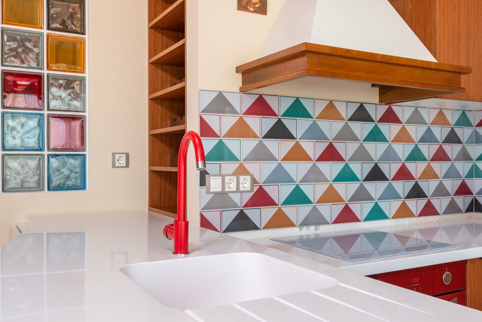 Stylish kitchen with colorful tile and a red faucet.