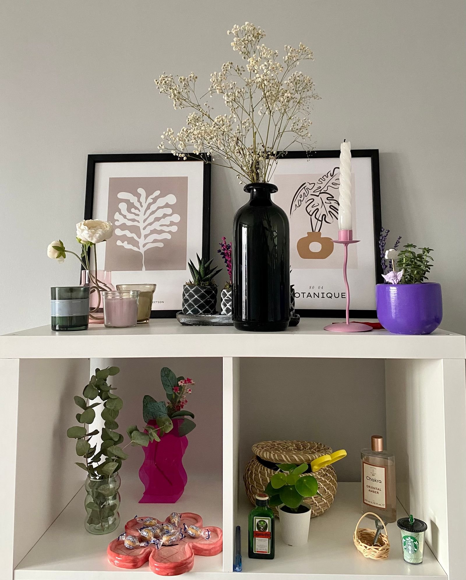 Modern shelf styled with vases, plants and framed art prints.