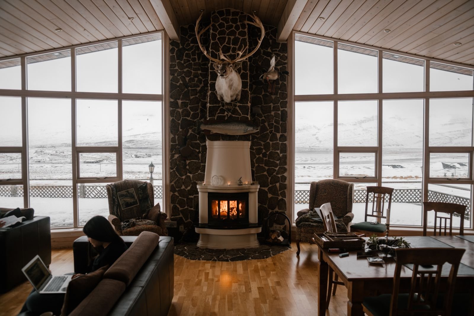 Cozy living room with a fireplace and windows facing snowy mountains.
