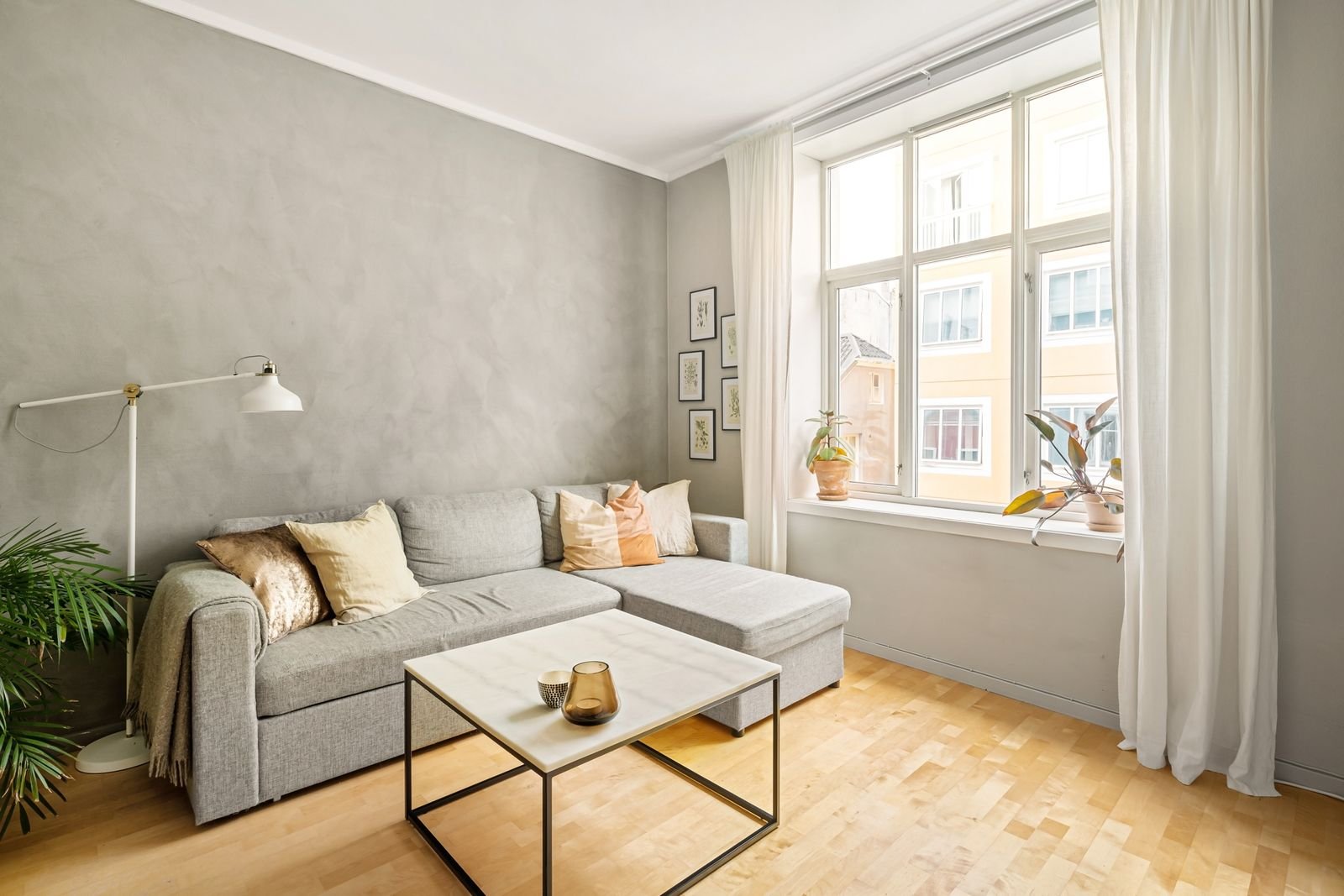 Bright monochrome living room with a gray sofa and a large window.