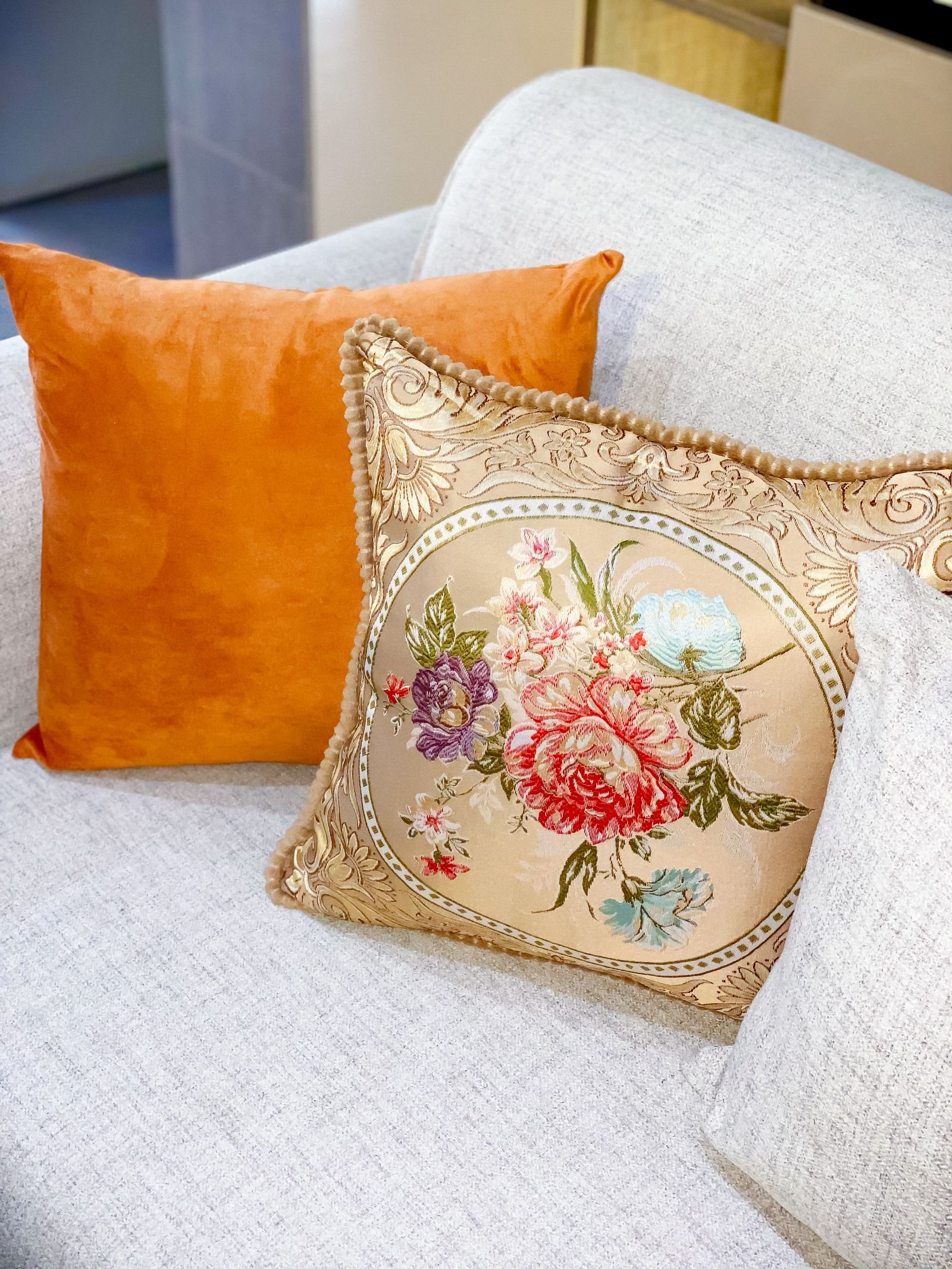 Floral and orange cushions on a light-colored sofa.