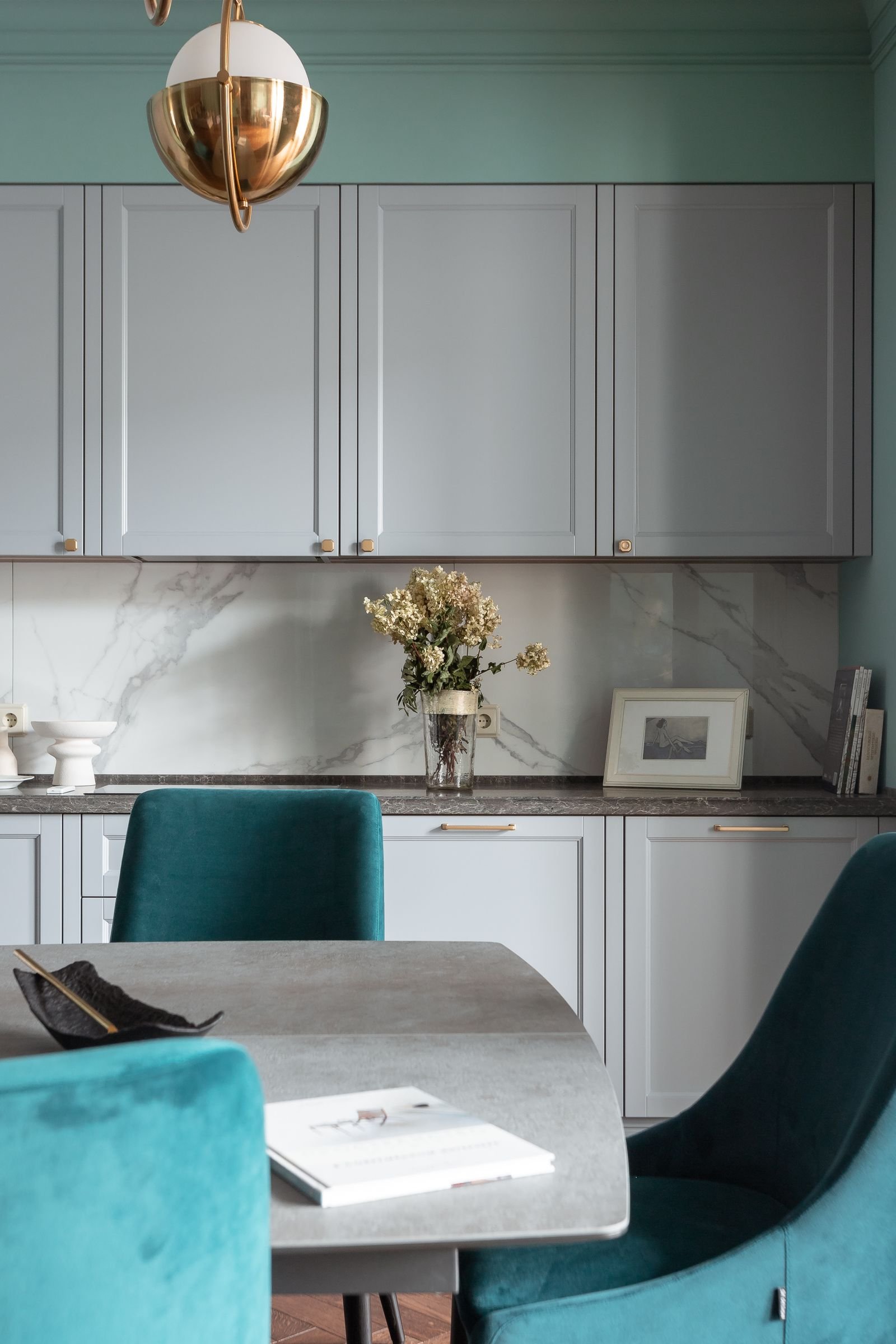 Kitchen with teal chairs, a gray table and marble accents.