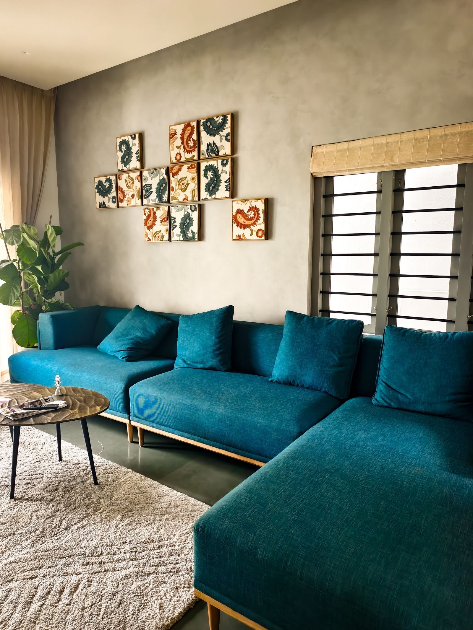 Living room with a teal sofa, modern art and natural light.