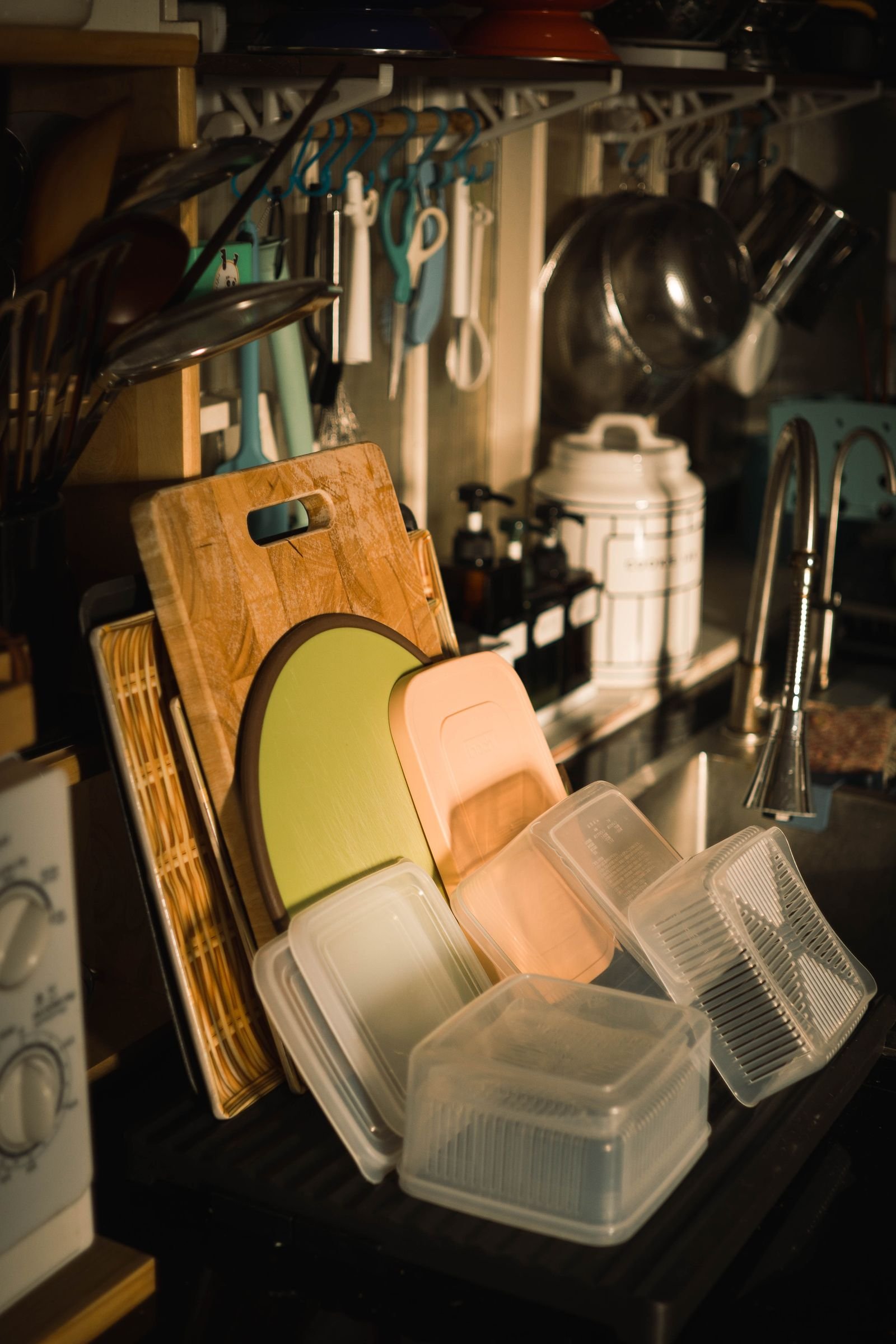 Organized kitchen sink area with cutting boards and storage containers.