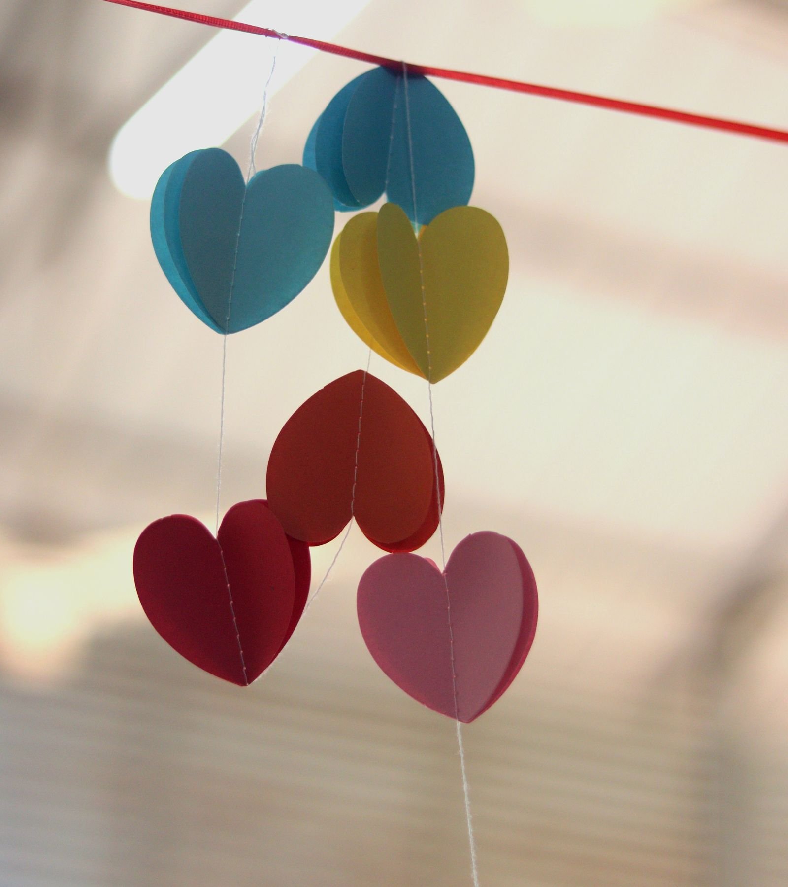 Heart-shaped paper garland hanging on a string indoors.