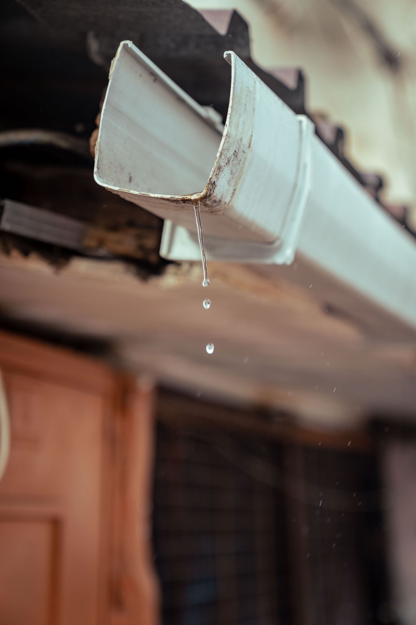Rainwater dripping from a house gutter.