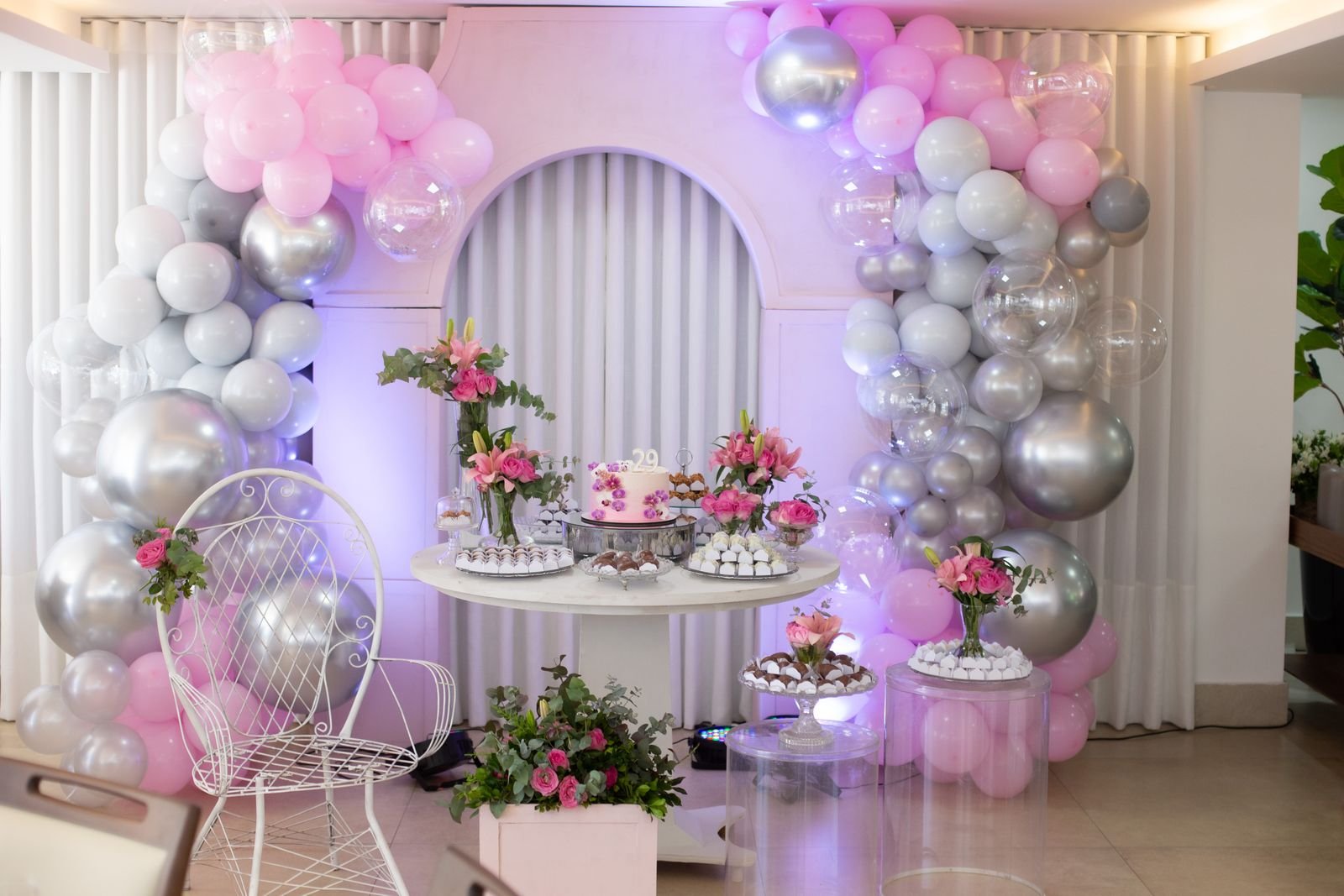 Birthday dessert table with pink and silver balloons and flowers.