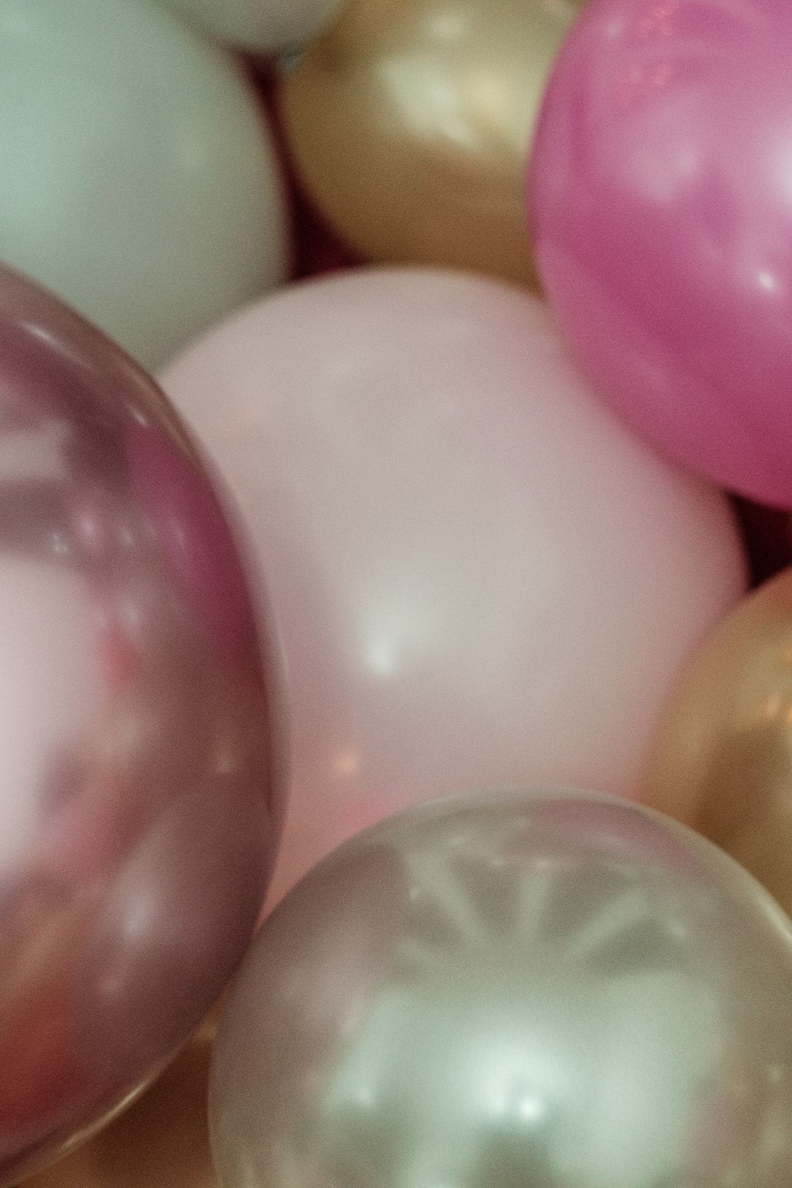 Pink, gold and pastel balloons grouped together.